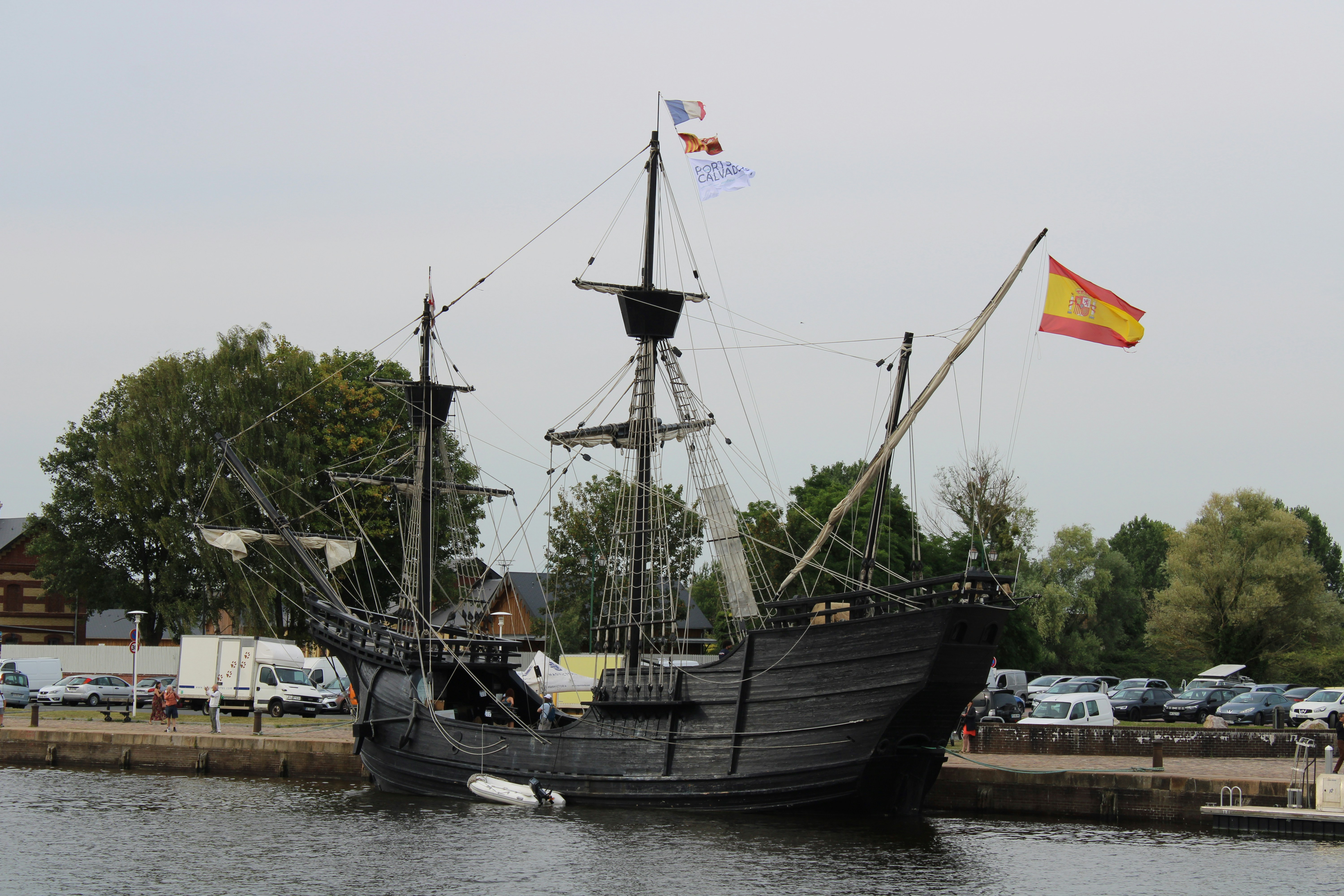 A large black boat in the water next to a dock