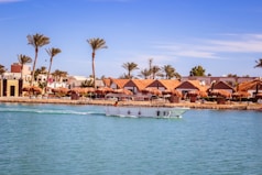 A boat traveling down a river next to a beach