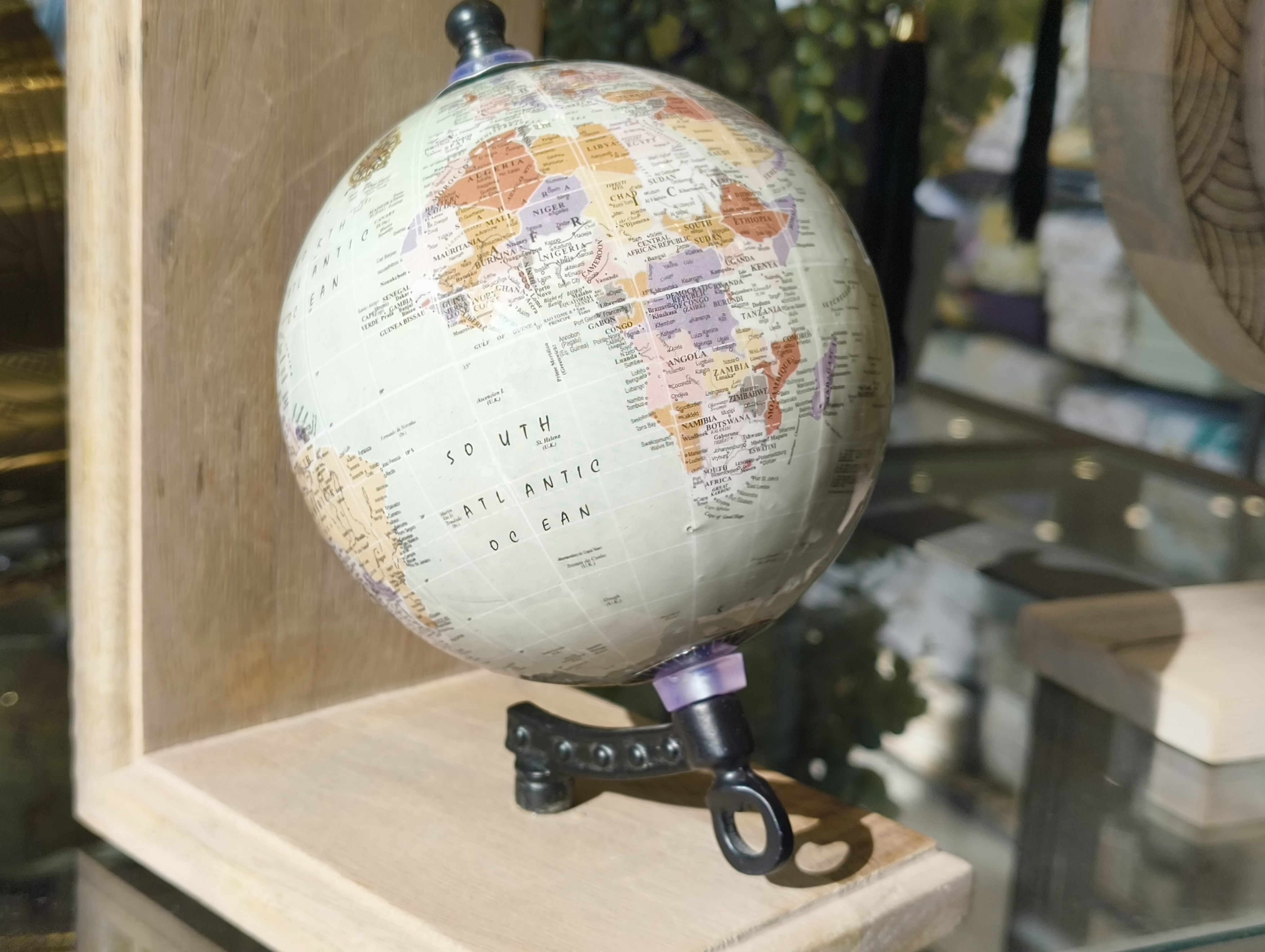 A small globe on a wooden stand with a pair of scissors