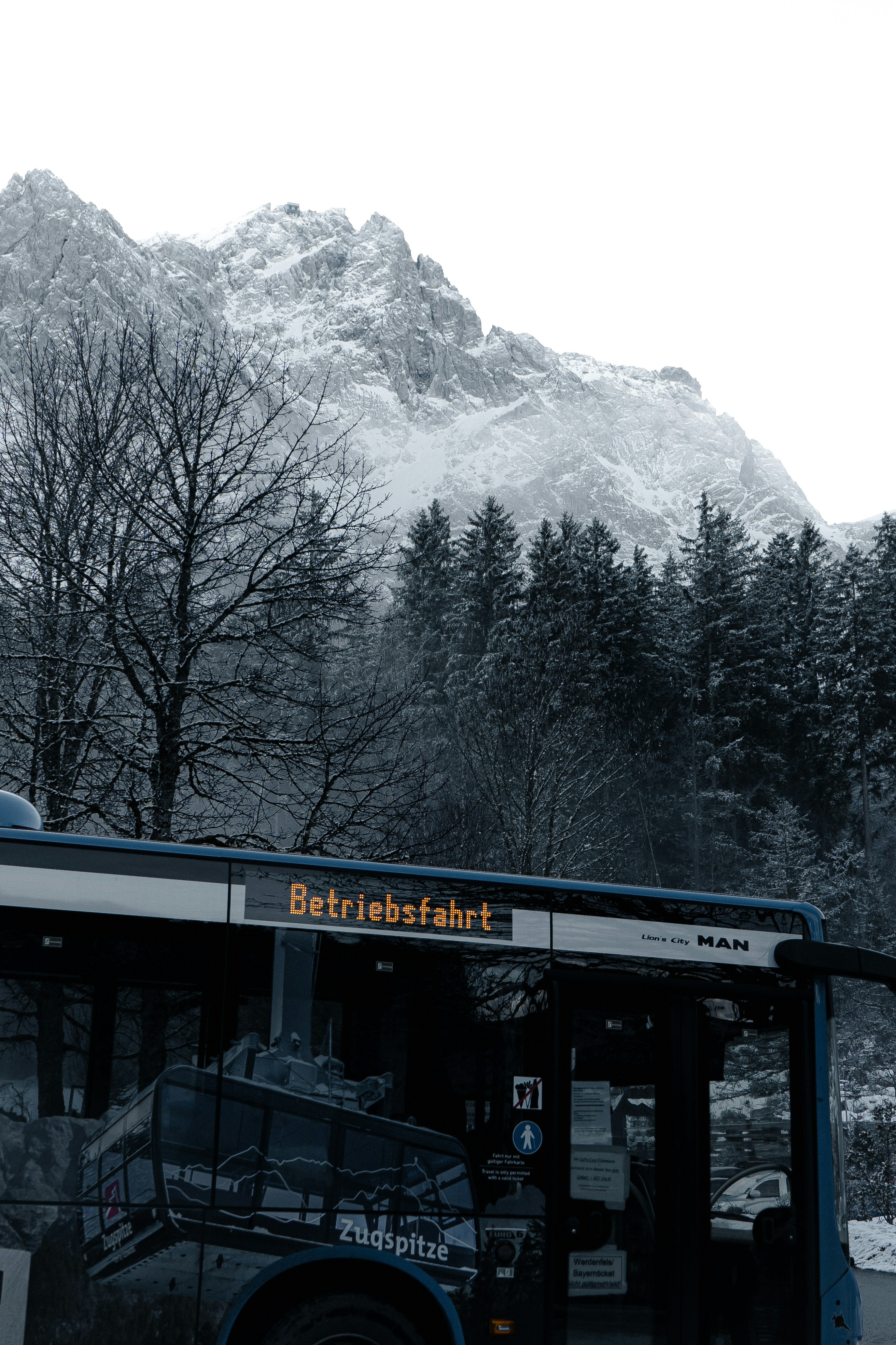 A black and white photo of a bus in front of a mountain