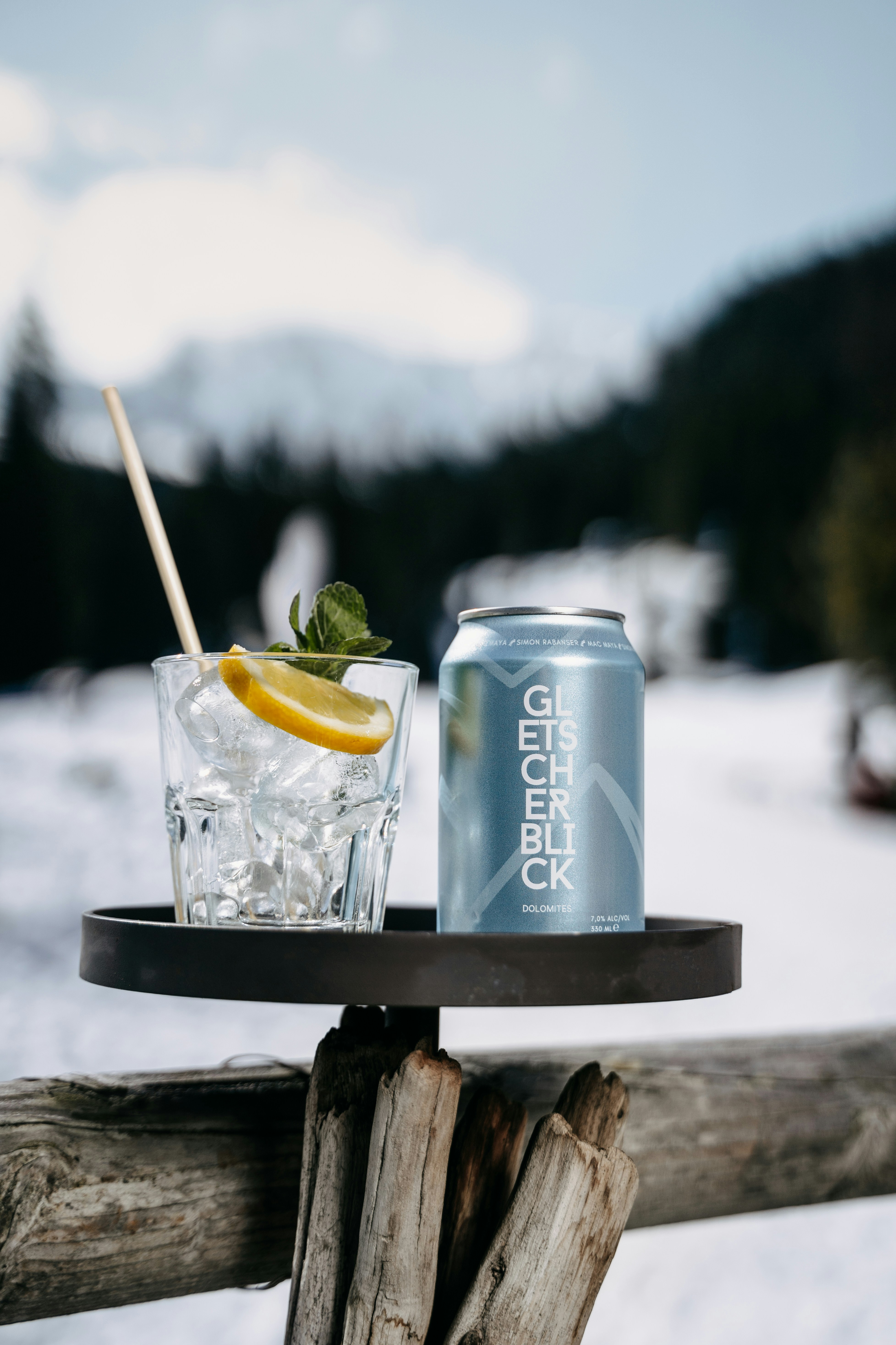 A can and a glass sitting on a table in the snow