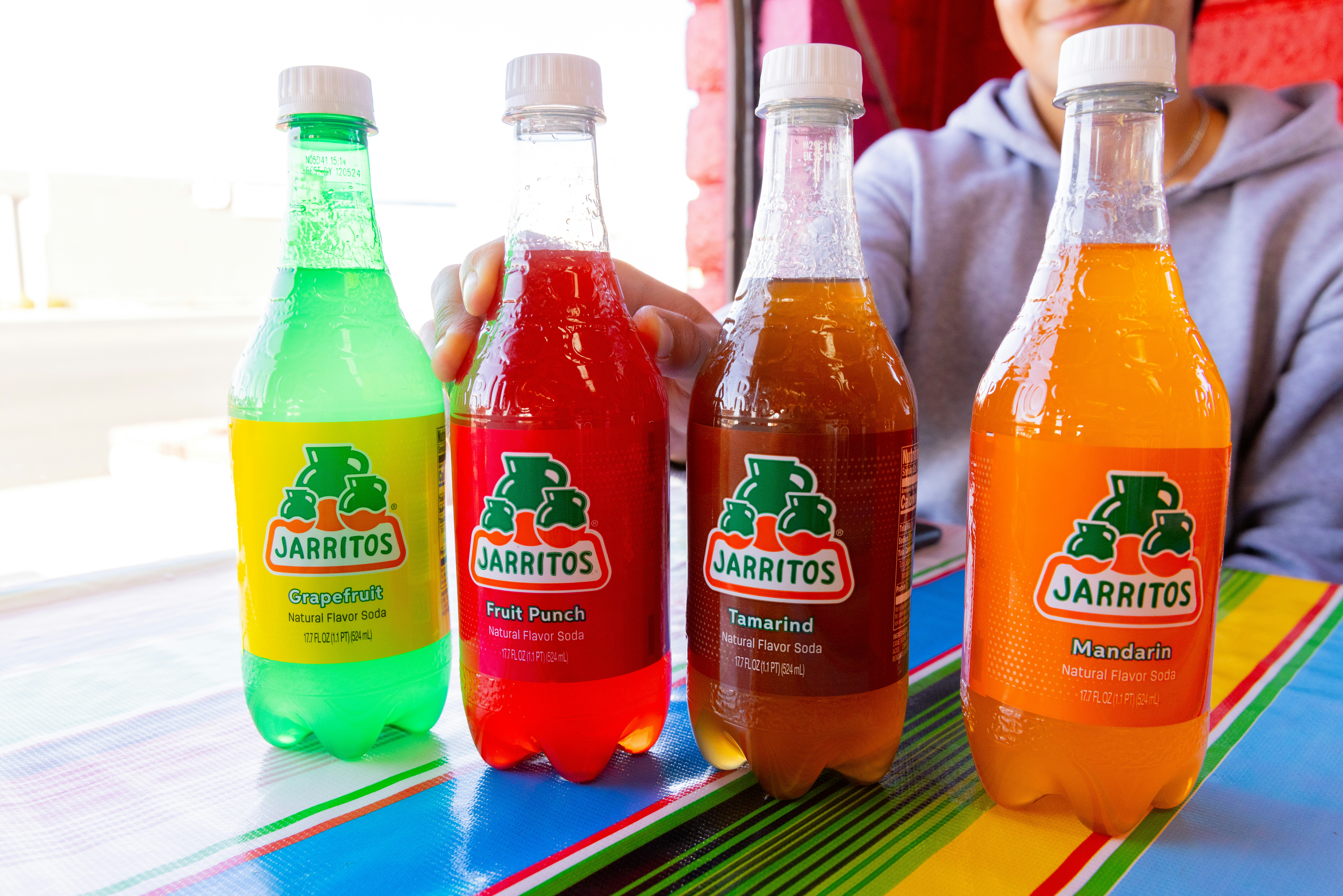 A man sitting at a table with three bottles of soda