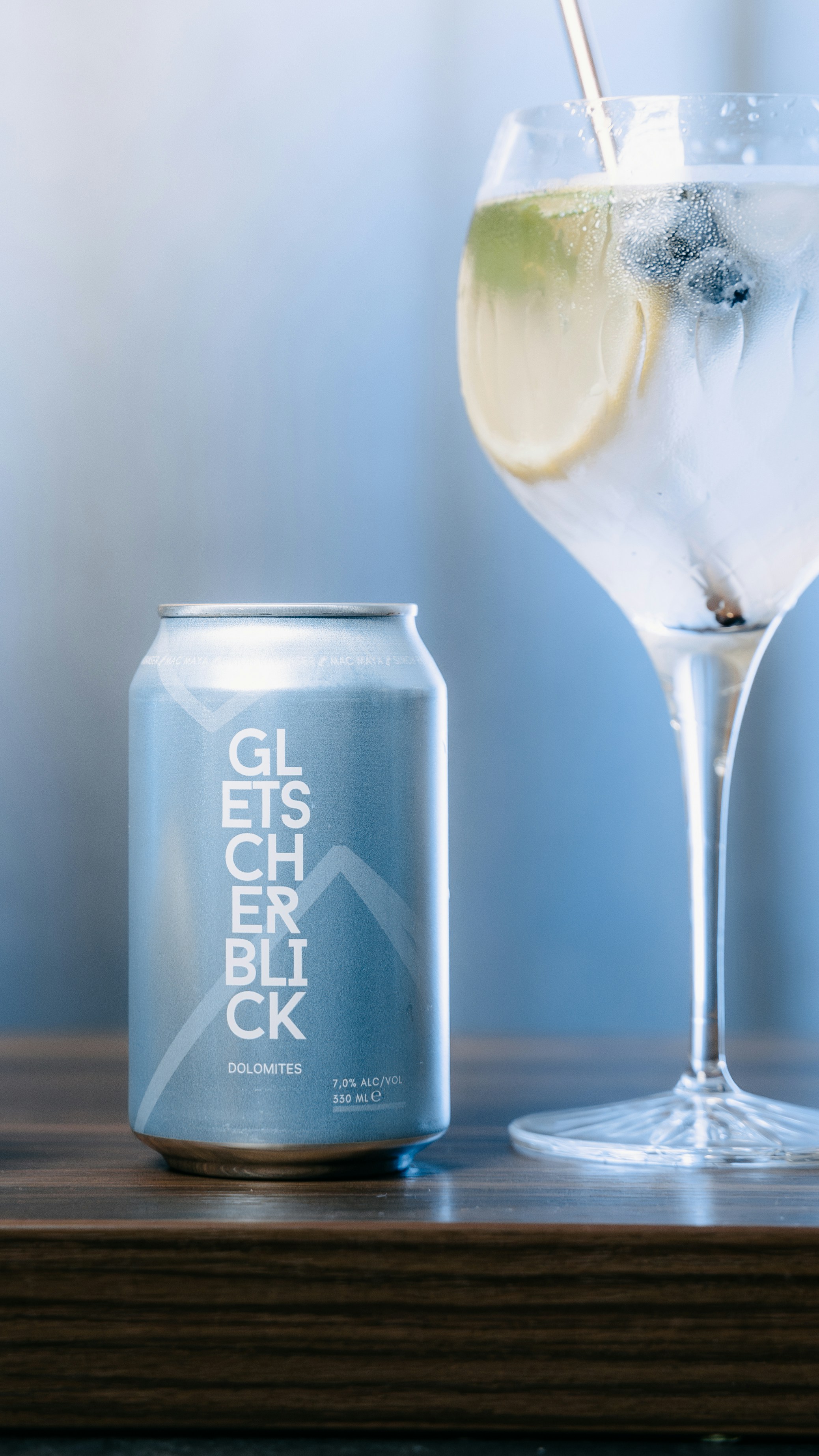 A glass of alcohol next to a can of soda