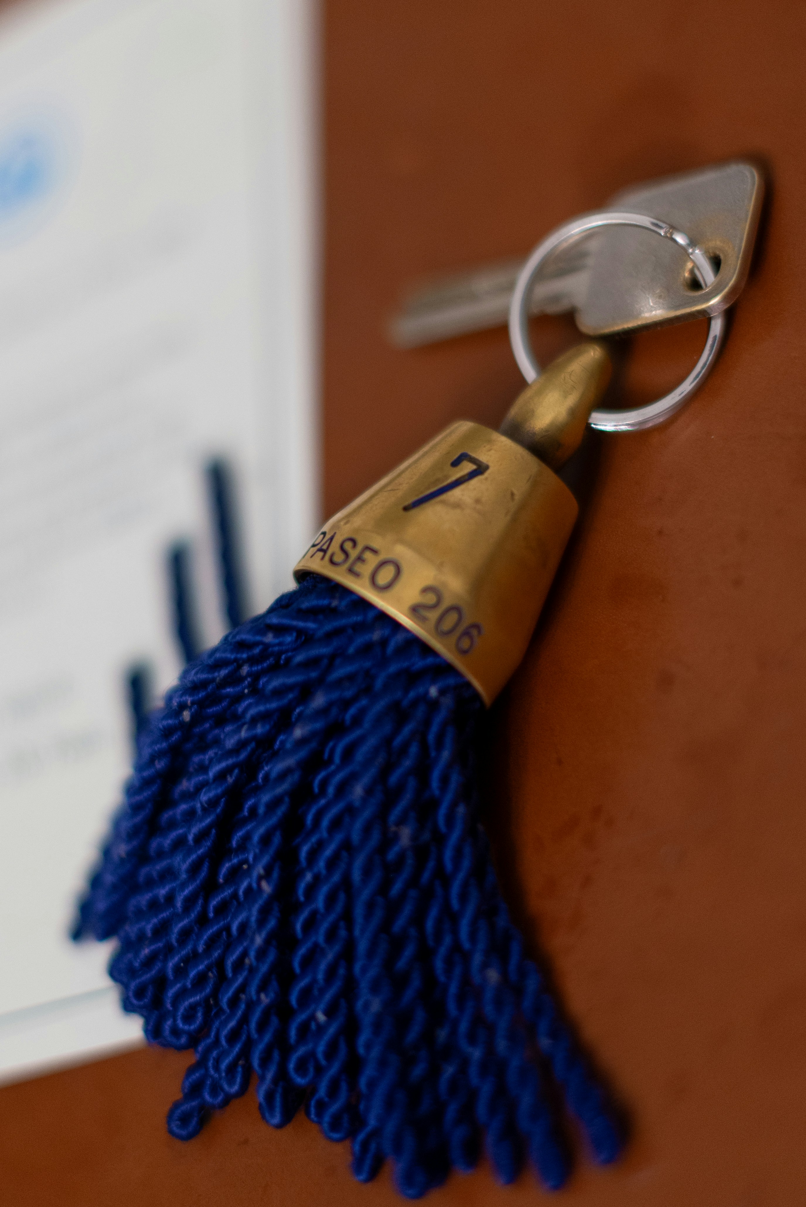 A blue tasseled keychain hanging on a wall