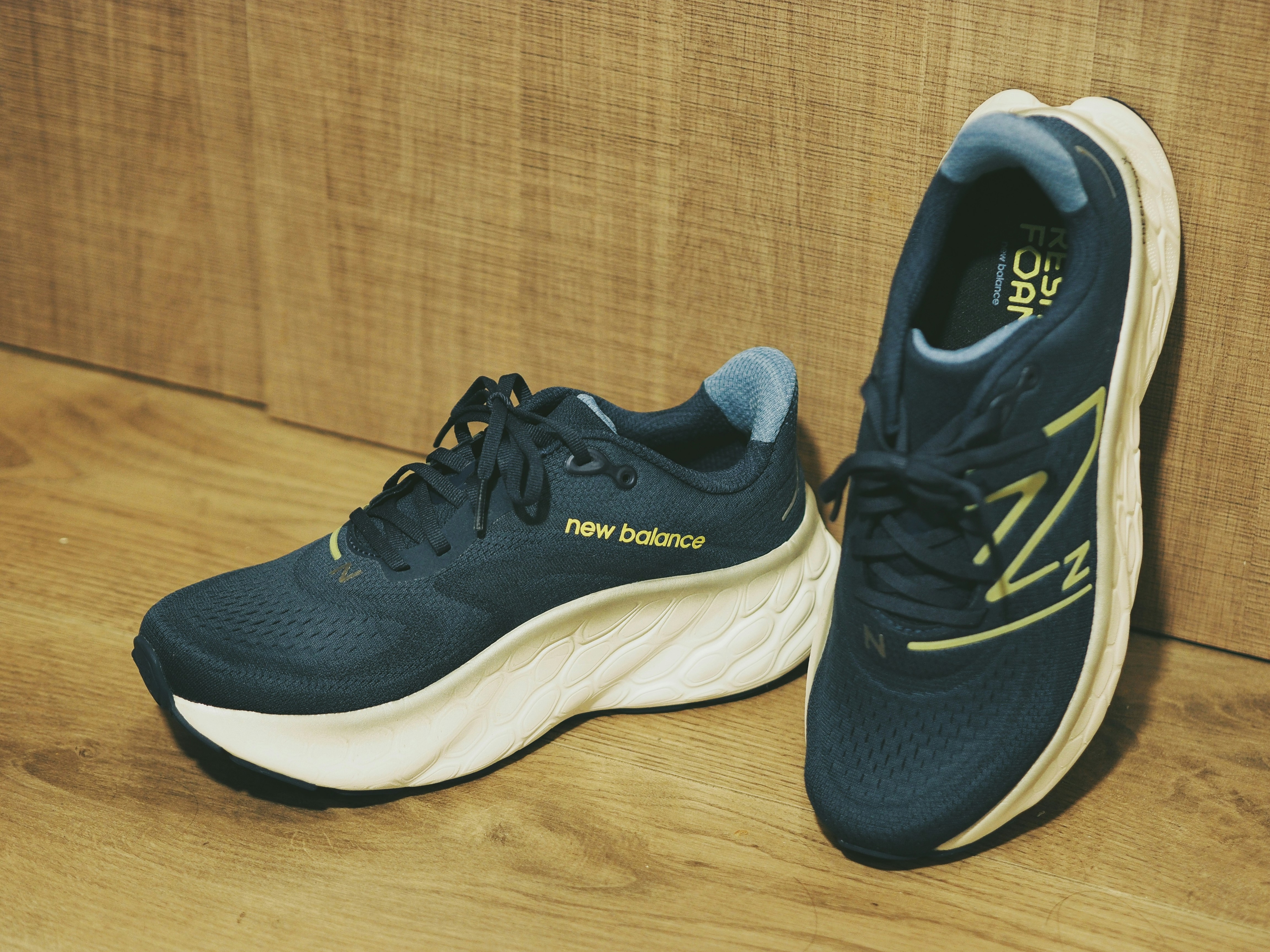 A pair of new balance shoes sitting on a wooden floor