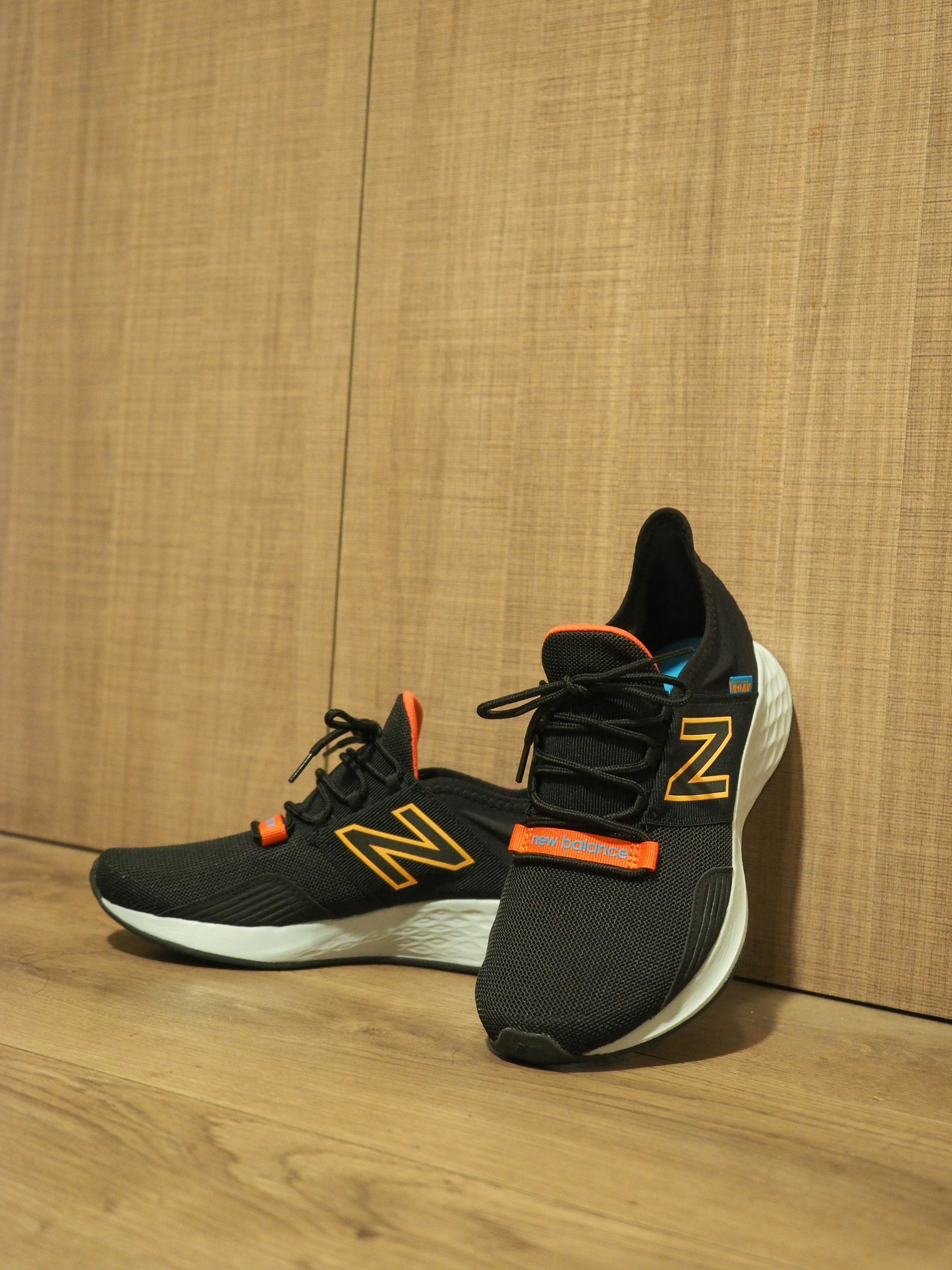 A pair of new balance shoes sitting on top of a wooden floor