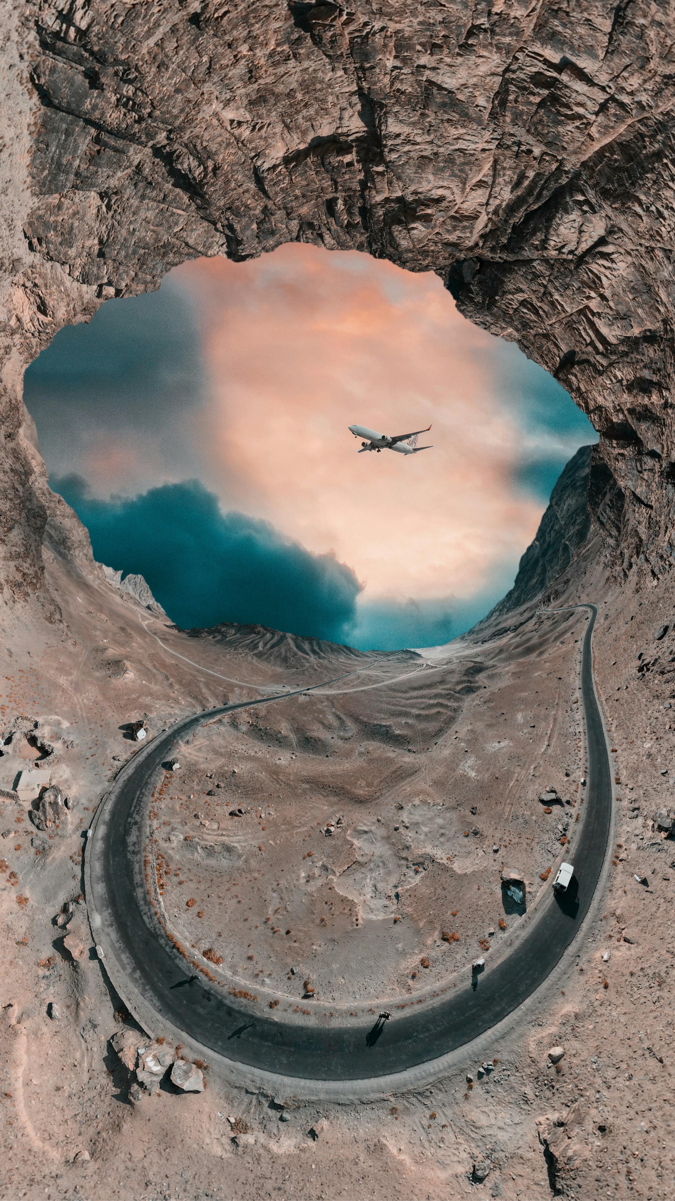 An airplane flying over a mountain with a road going through it