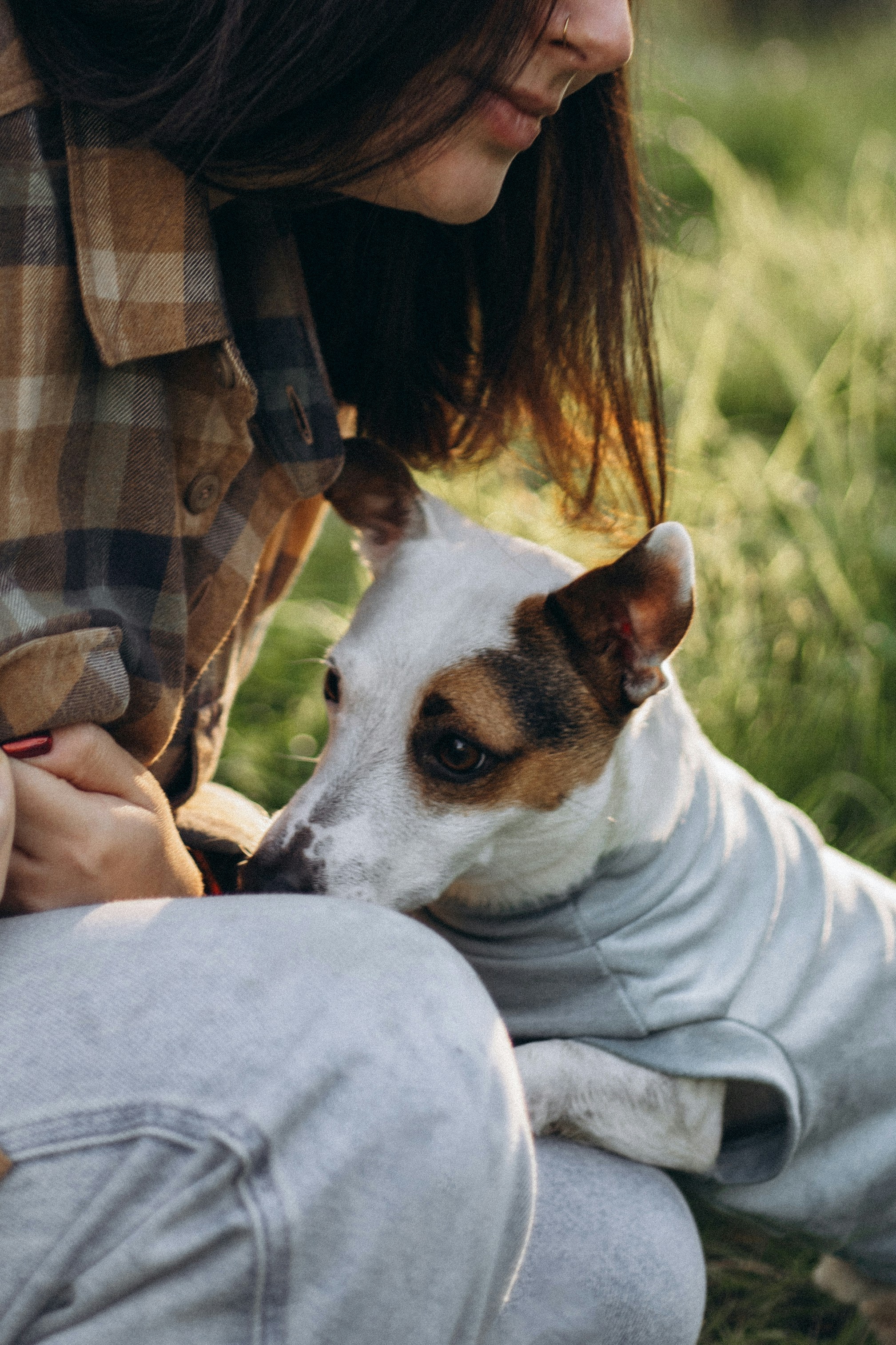 A woman petting a dog wearing a sweater
