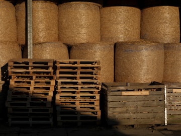 A pile of hay sitting next to a pile of wooden pallets