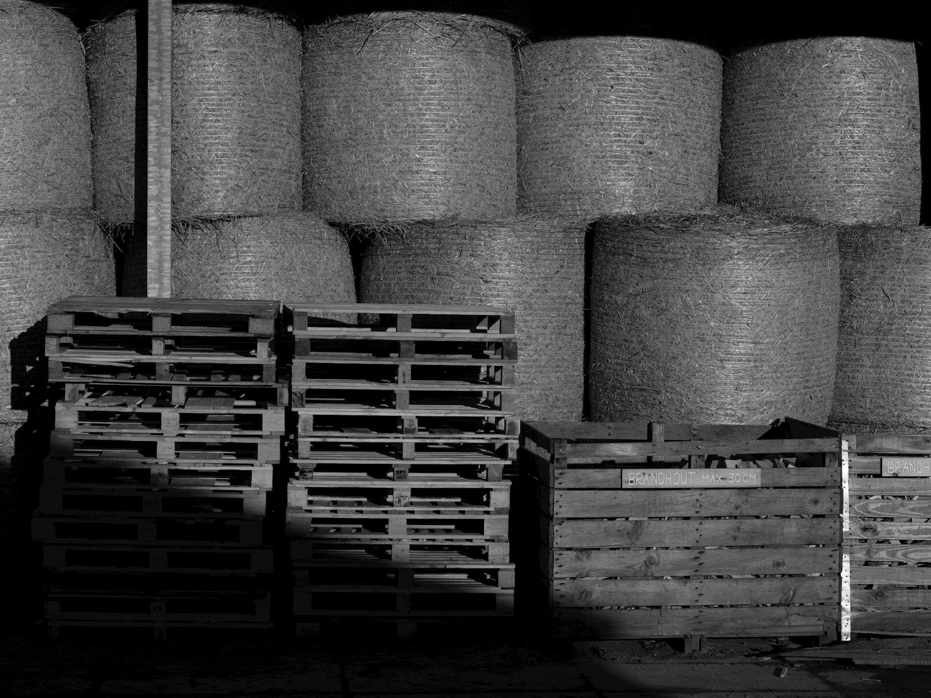A black and white photo of stacks of hay