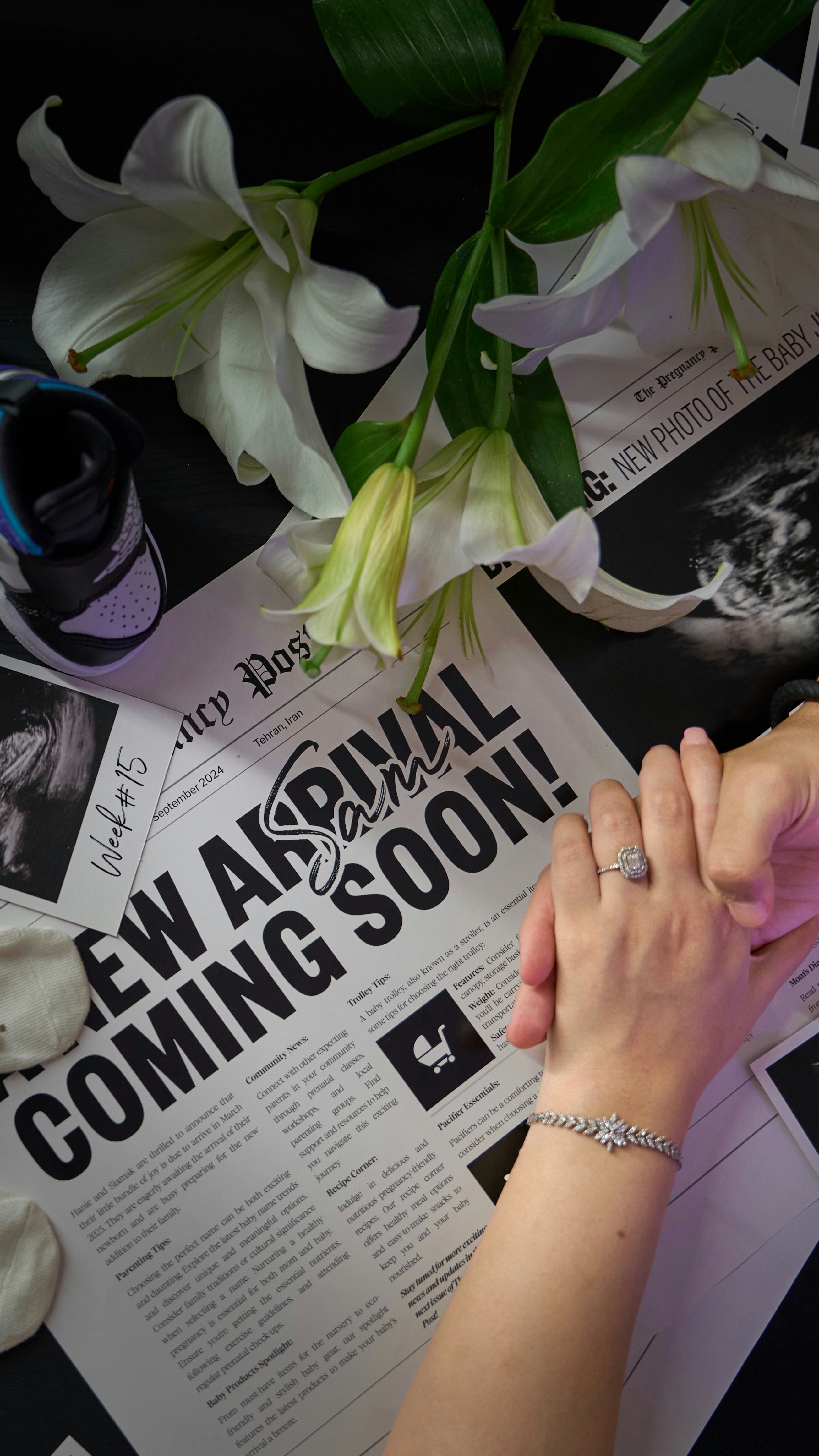 A woman's hands holding another woman's hand on top of a newspaper