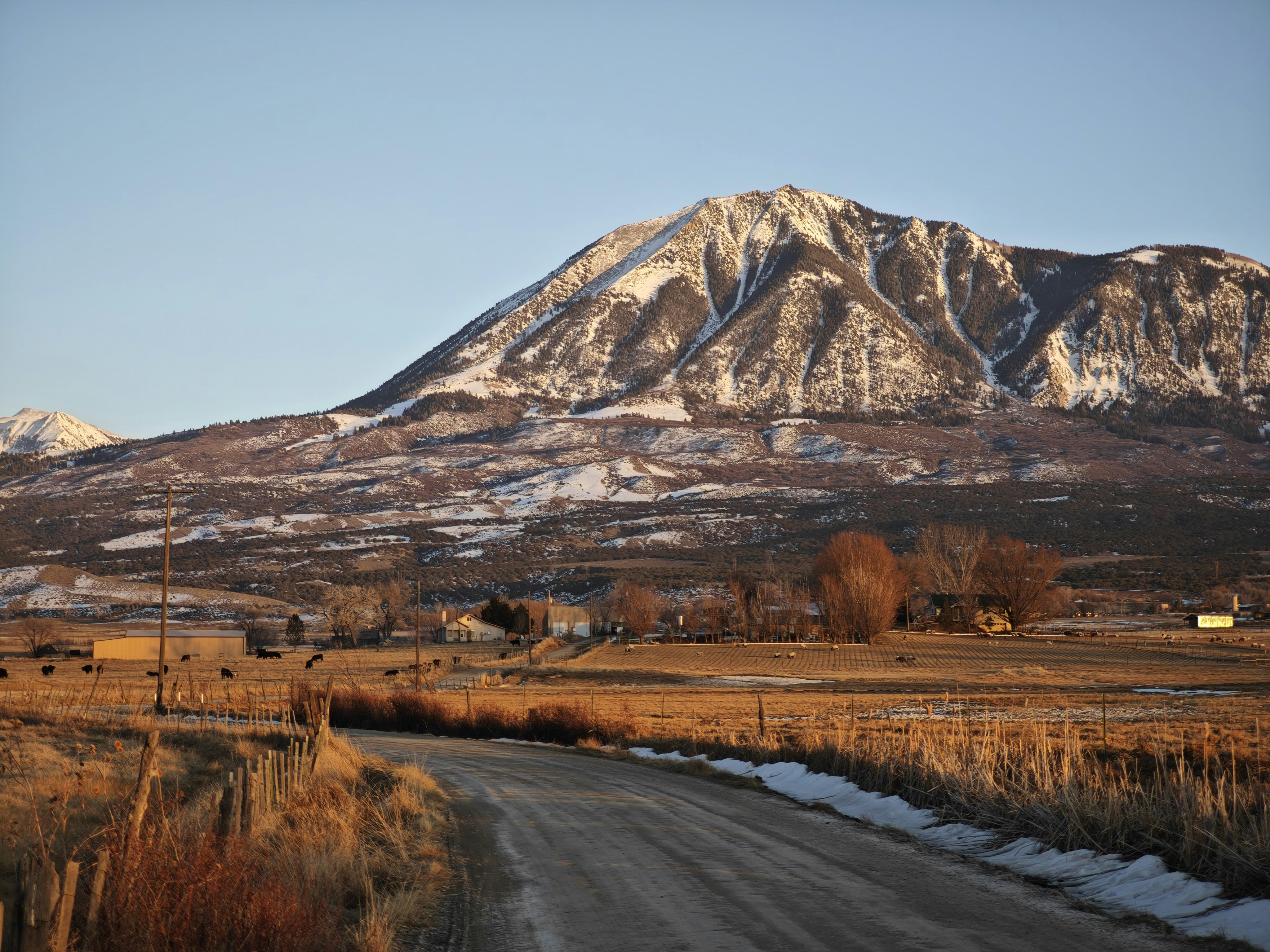 A dirt road in front of a snow covered mountain
