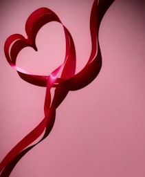 A heart shaped ribbon on a pink background