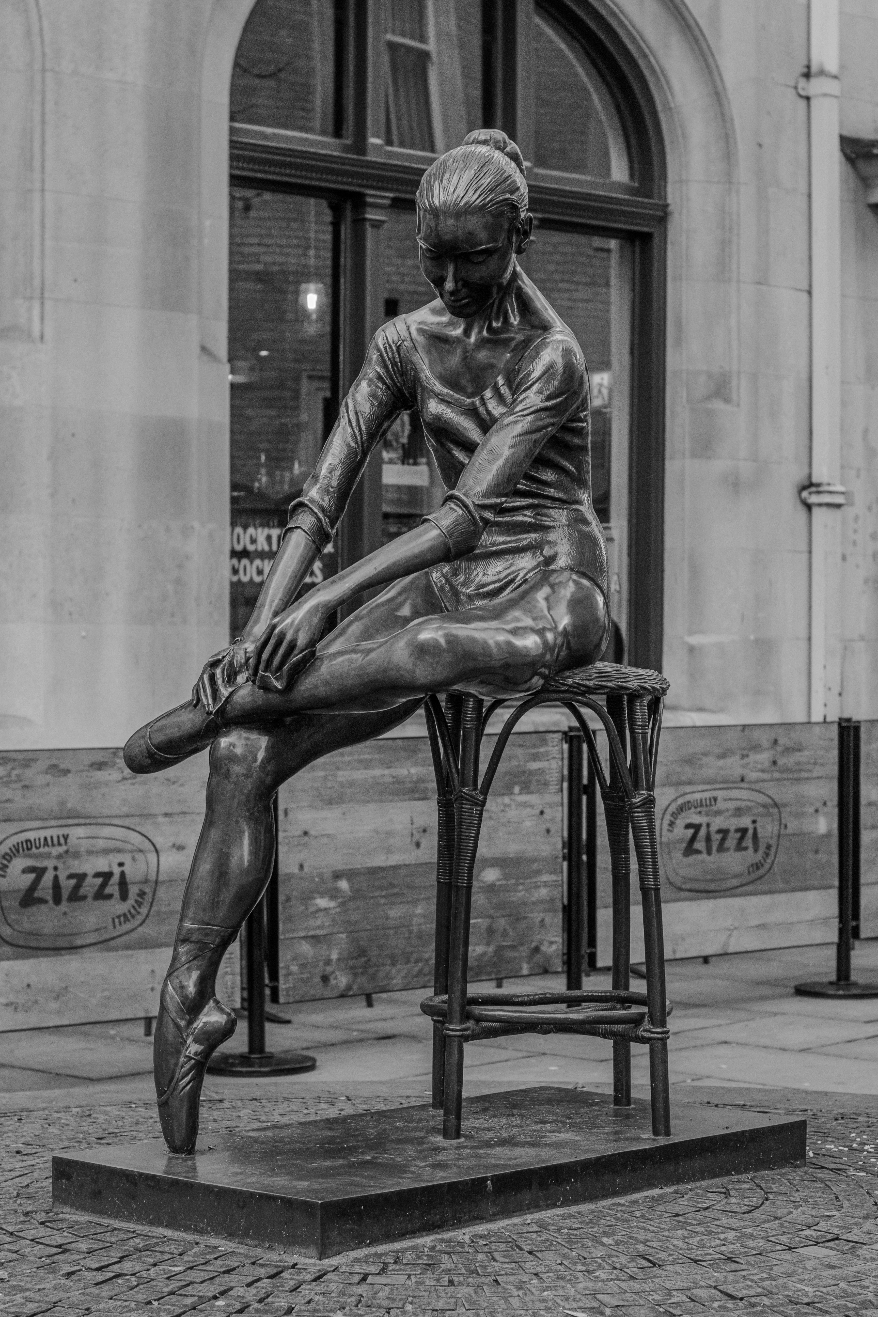 A black and white photo of a statue of a woman sitting on a chair