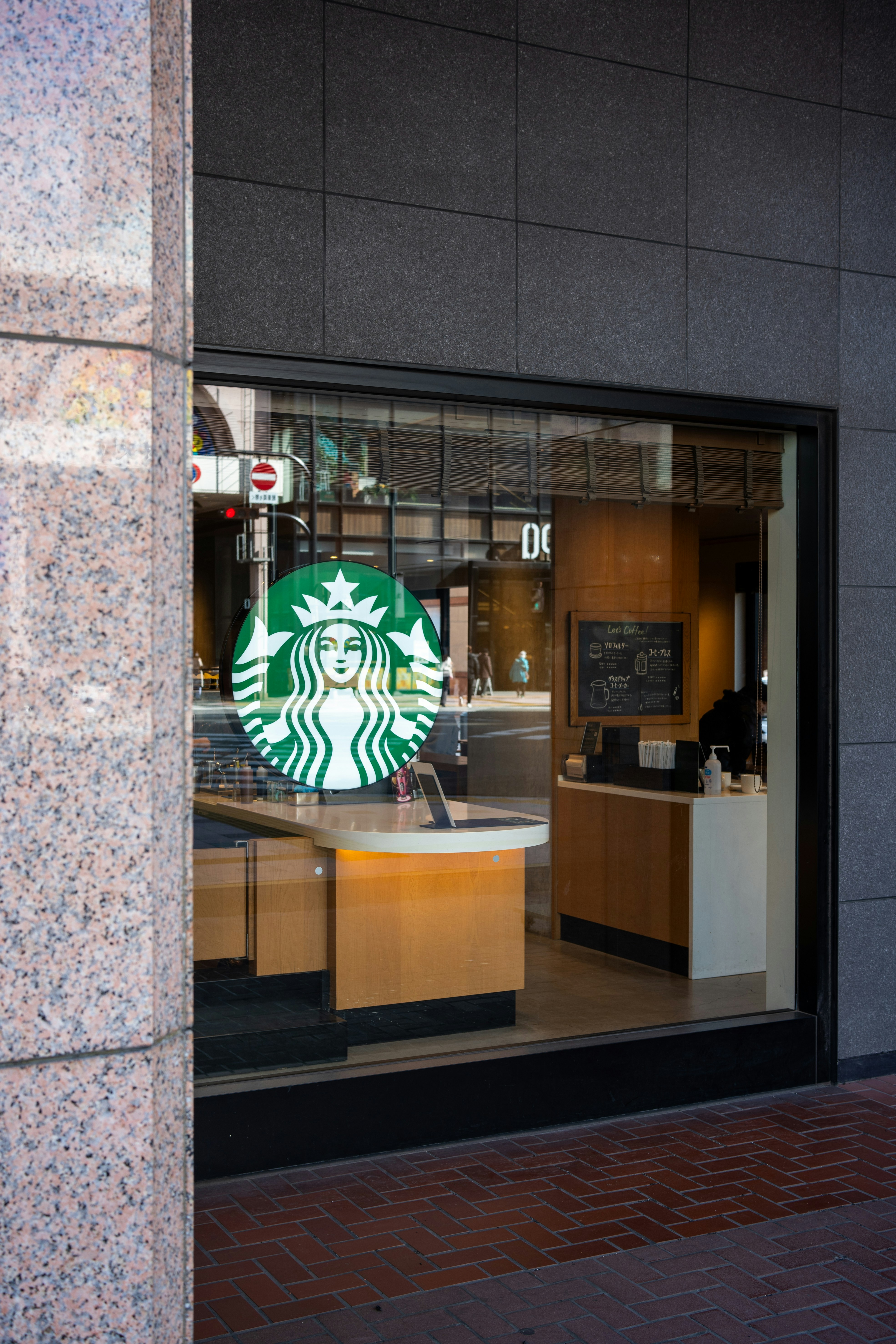 A starbucks sign is seen through the window of a coffee shop