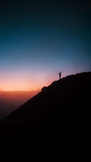A person standing on top of a hill at sunset