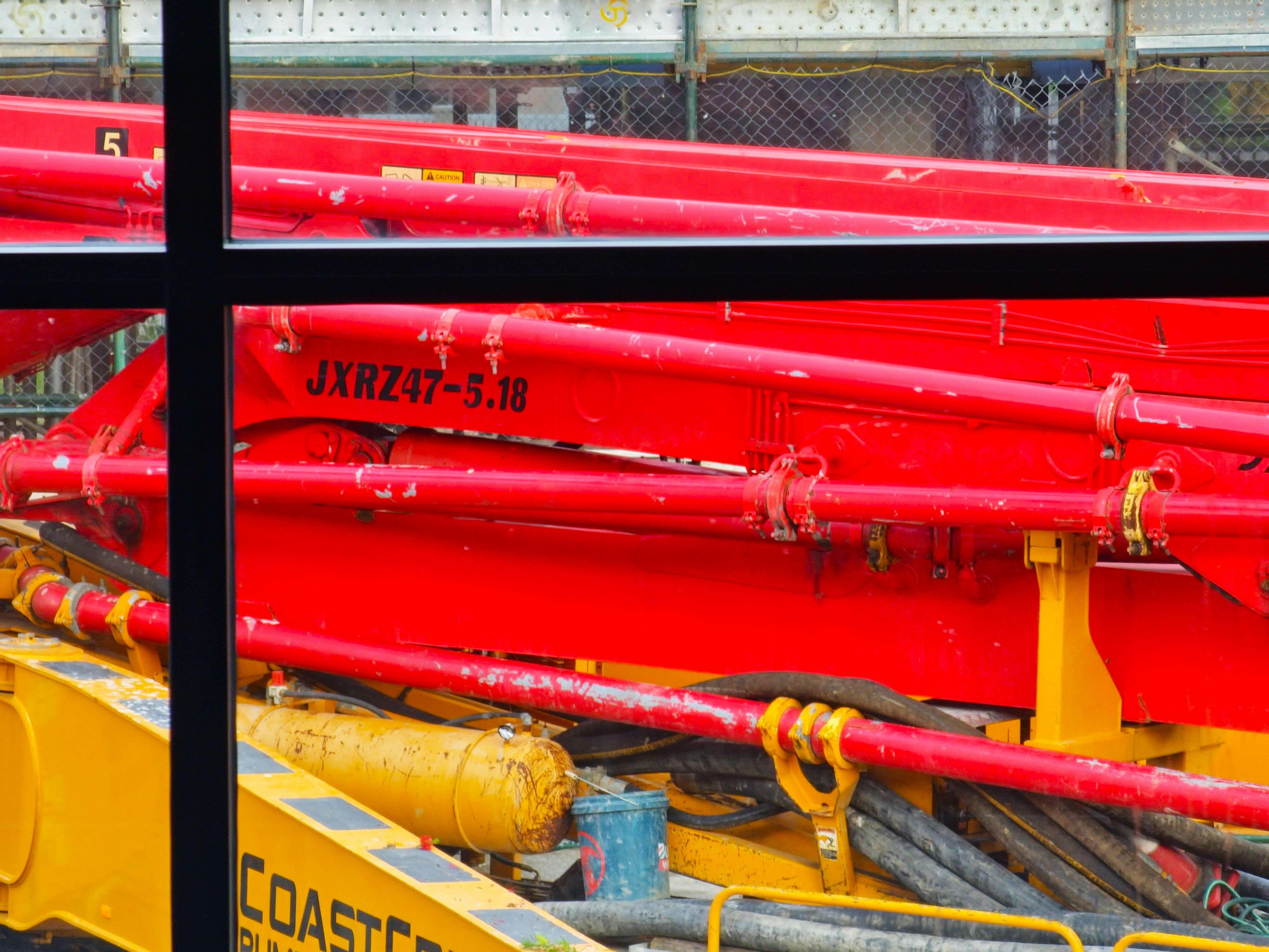 Red delivery pipes running along a pump boom in the sun