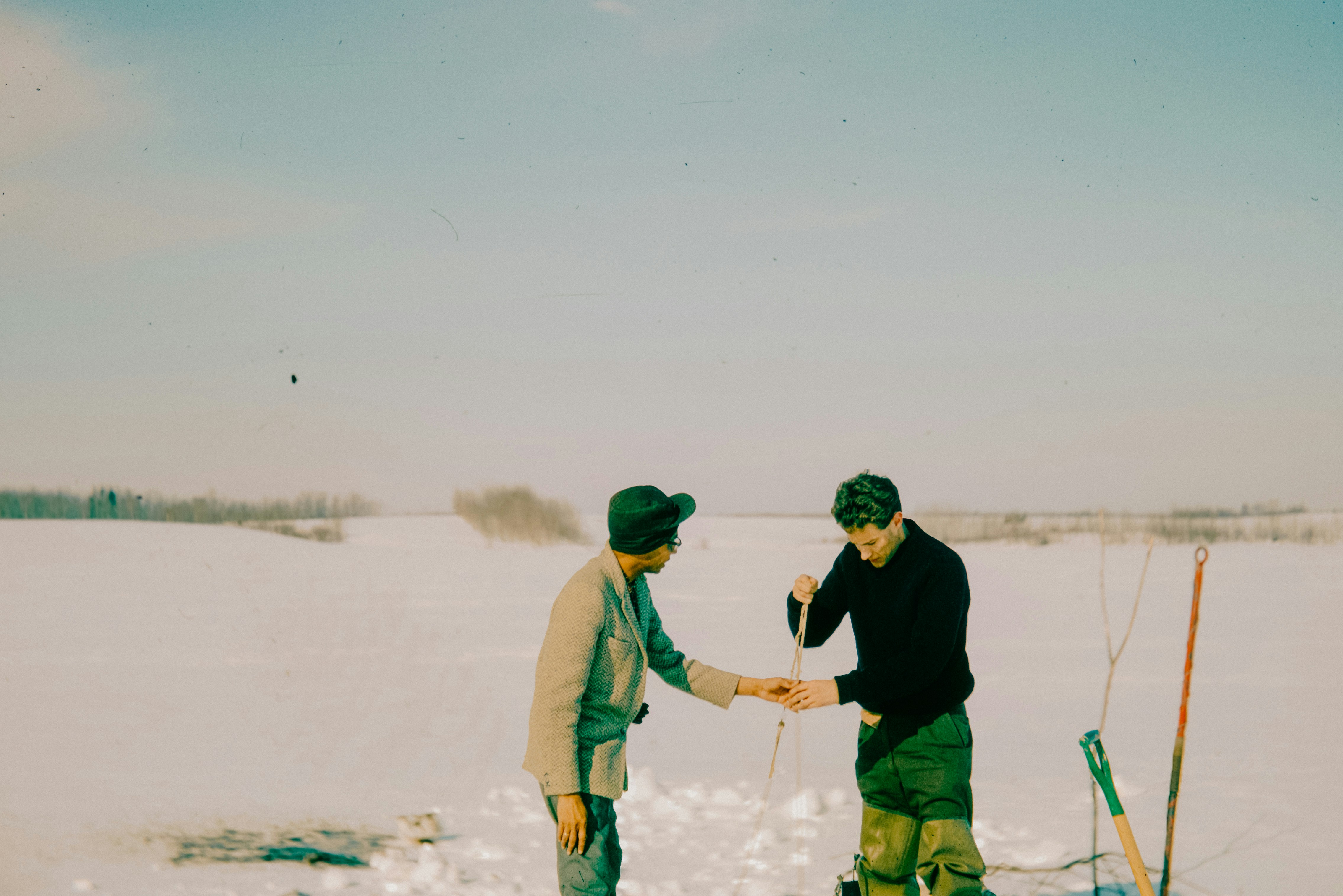 A couple of men standing on top of a snow covered field