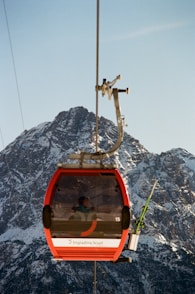 A red cable car going up a mountain