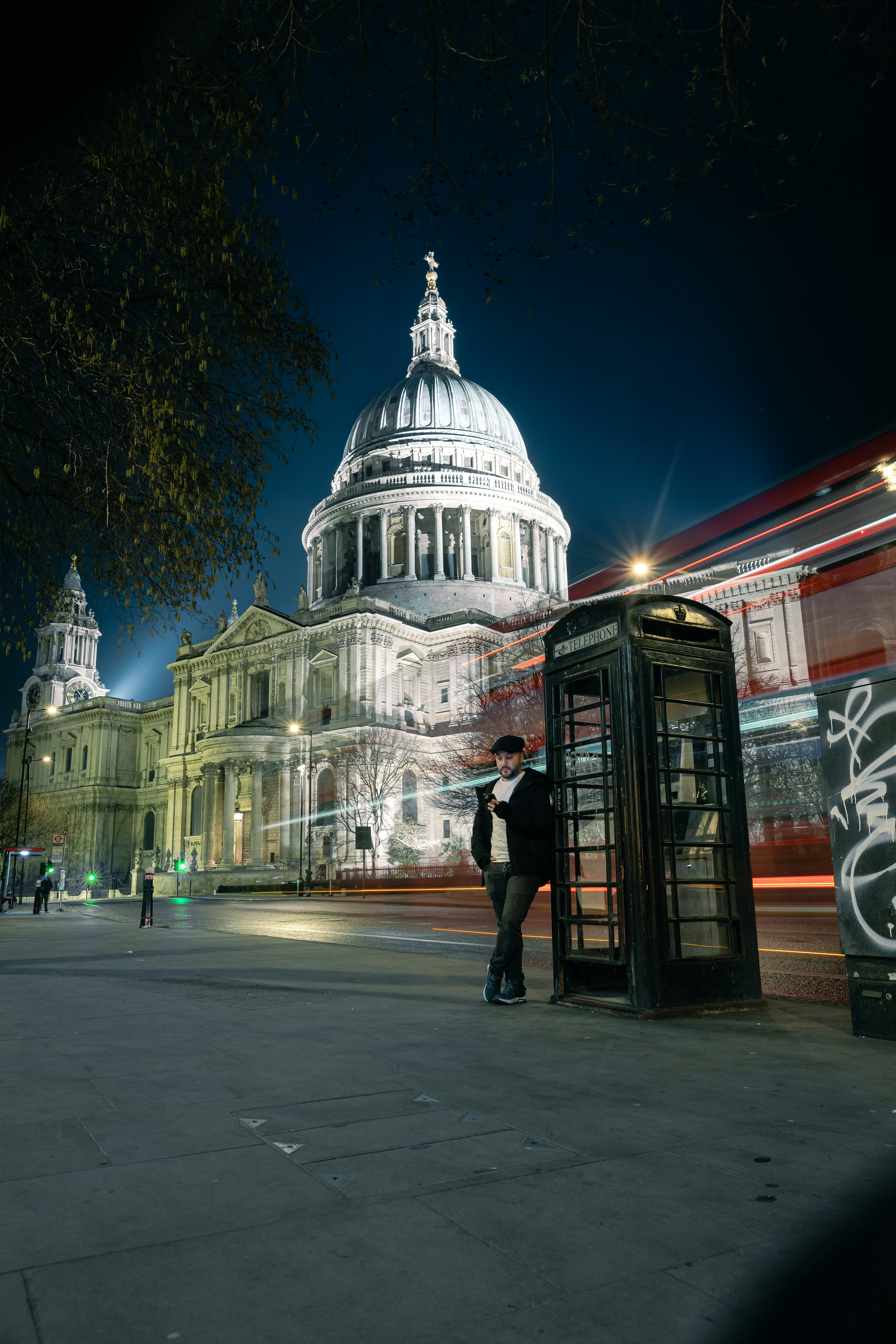 Un hombre de pie junto a una cabina telefónica frente a un edificio