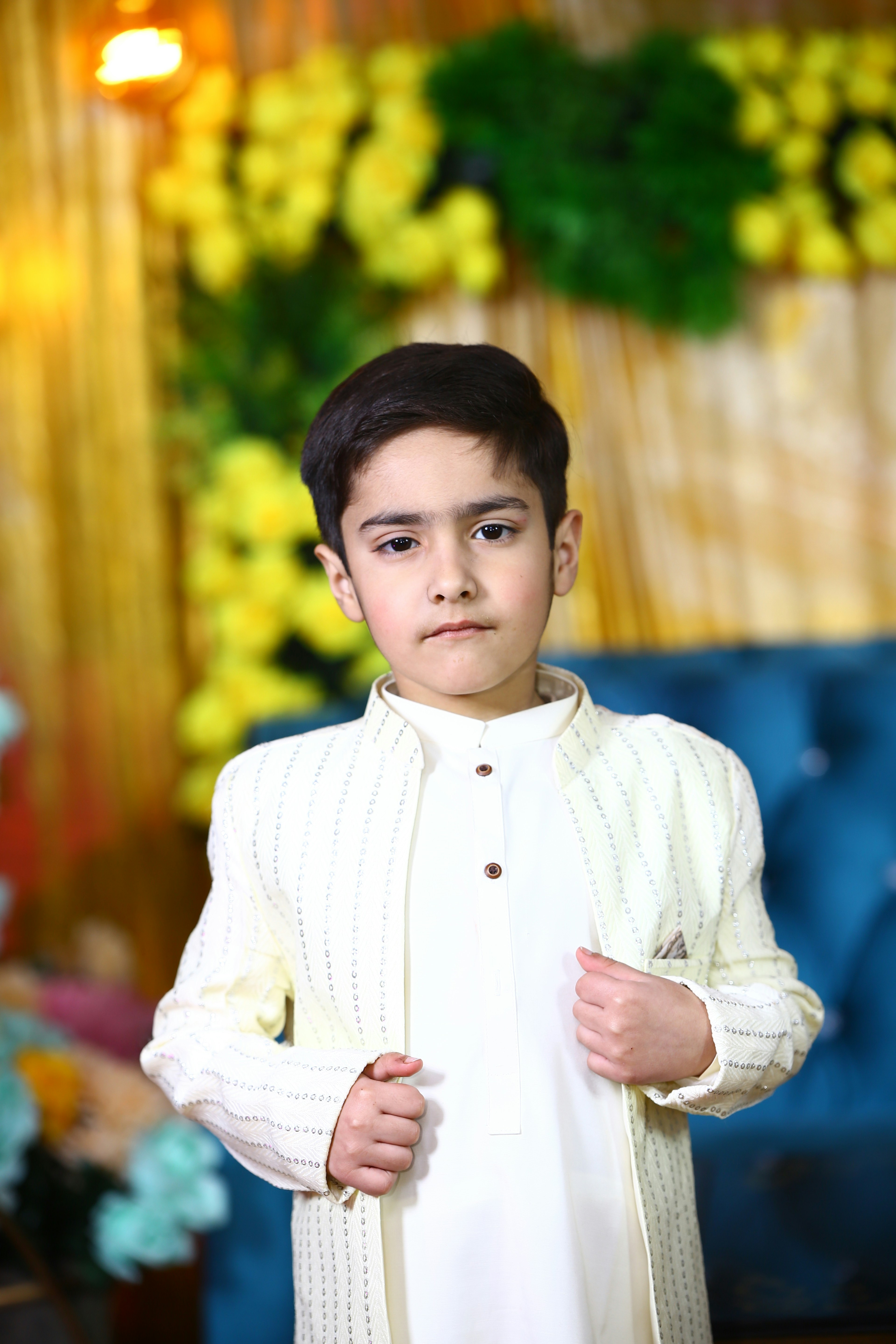 A young boy standing in front of a blue couch