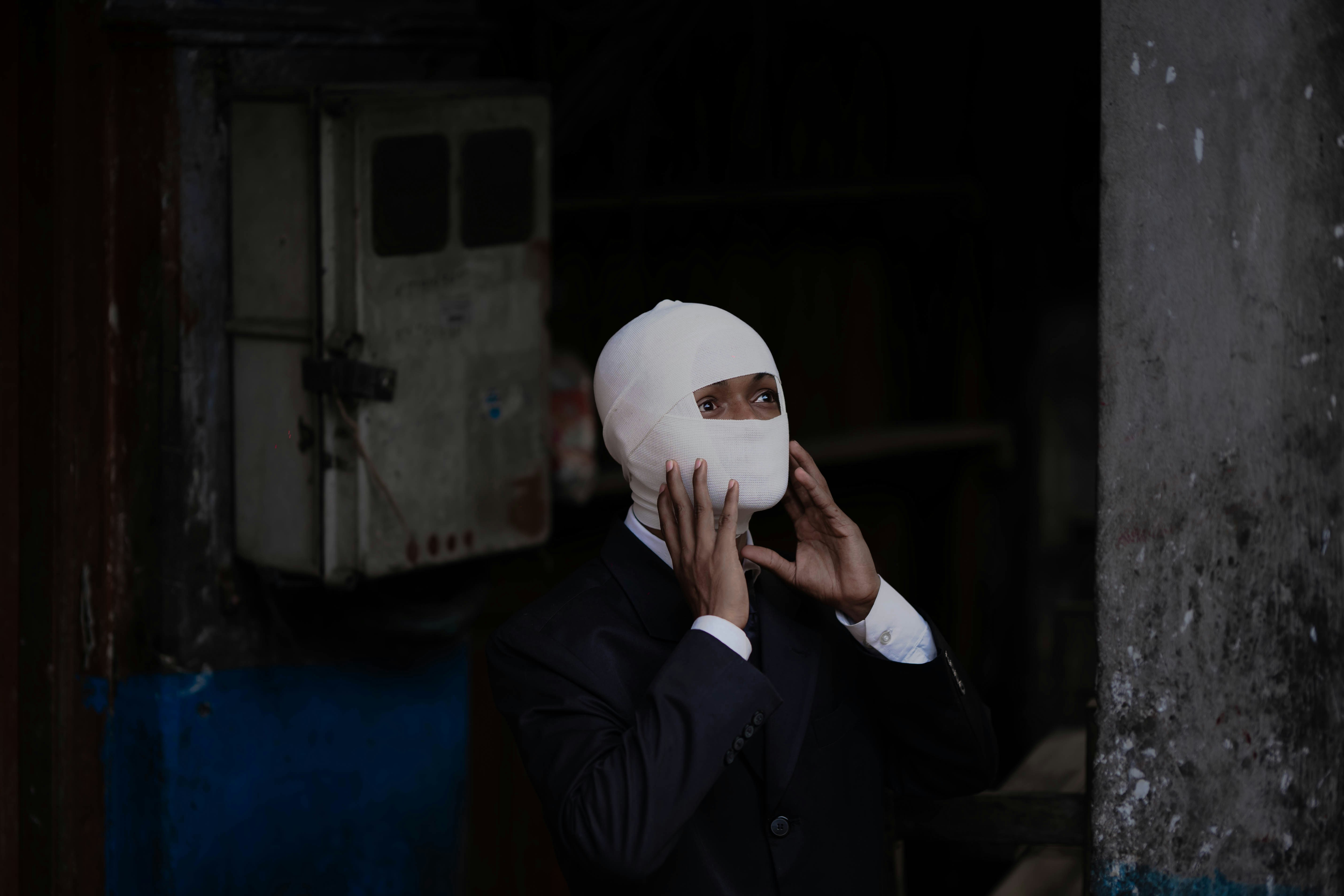 A man wearing a white mask talking on a cell phone