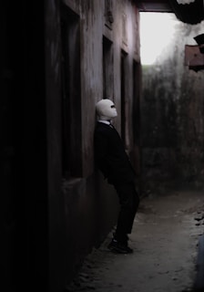 A man in a black suit and a white mask