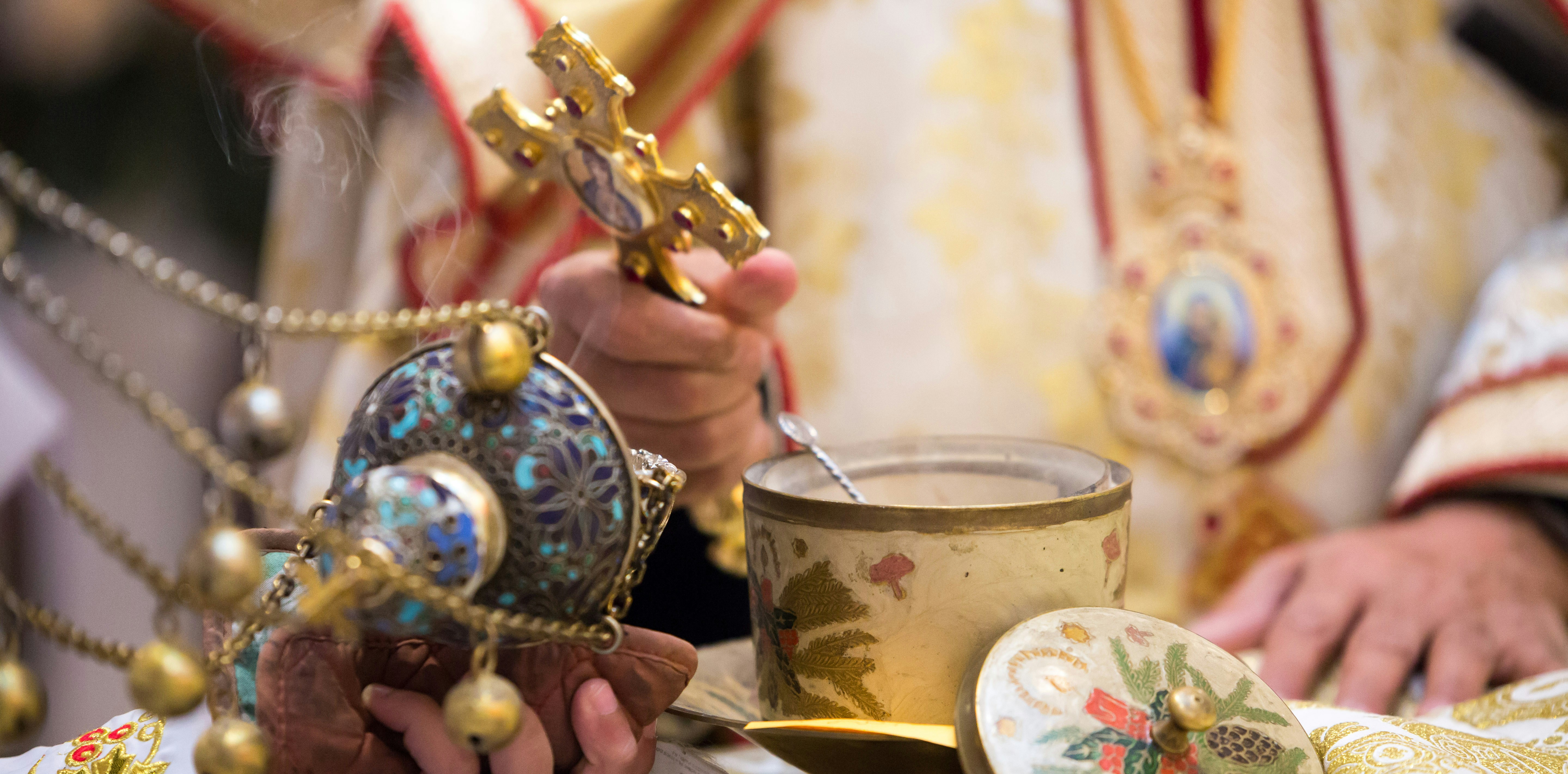 A priest is holding a cup and a cross