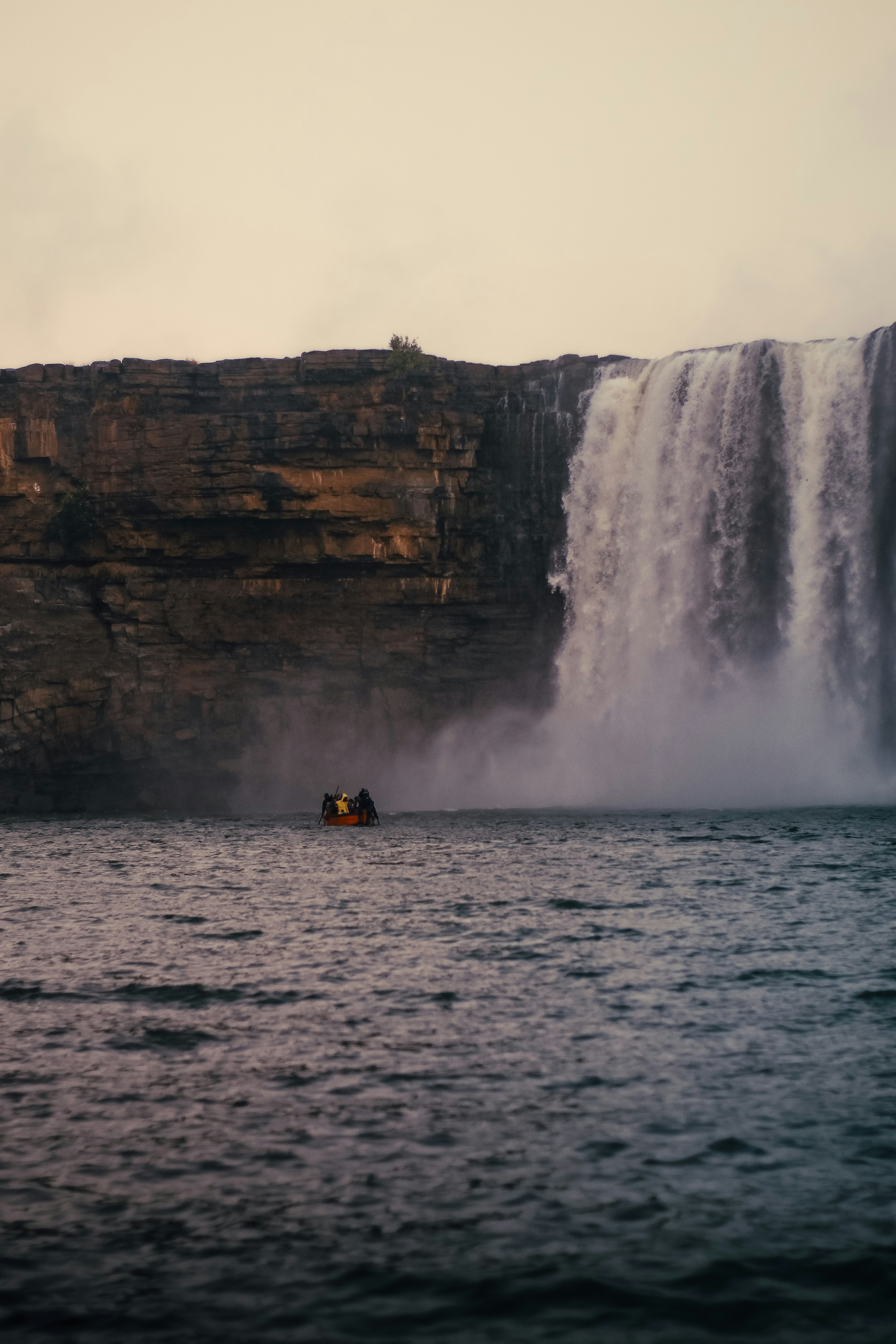 A boat in a body of water near a waterfall