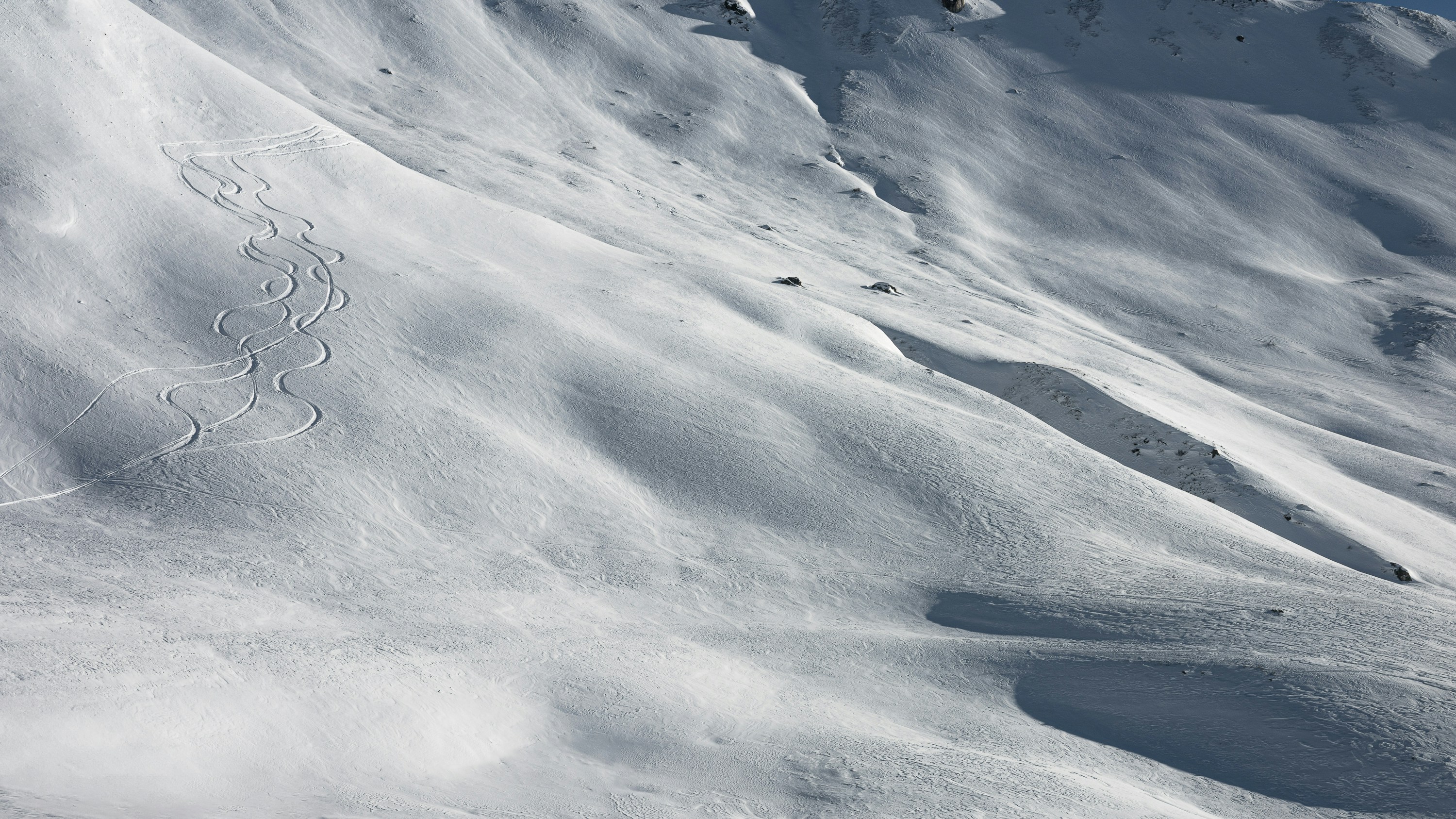 A man riding skis down the side of a snow covered slope