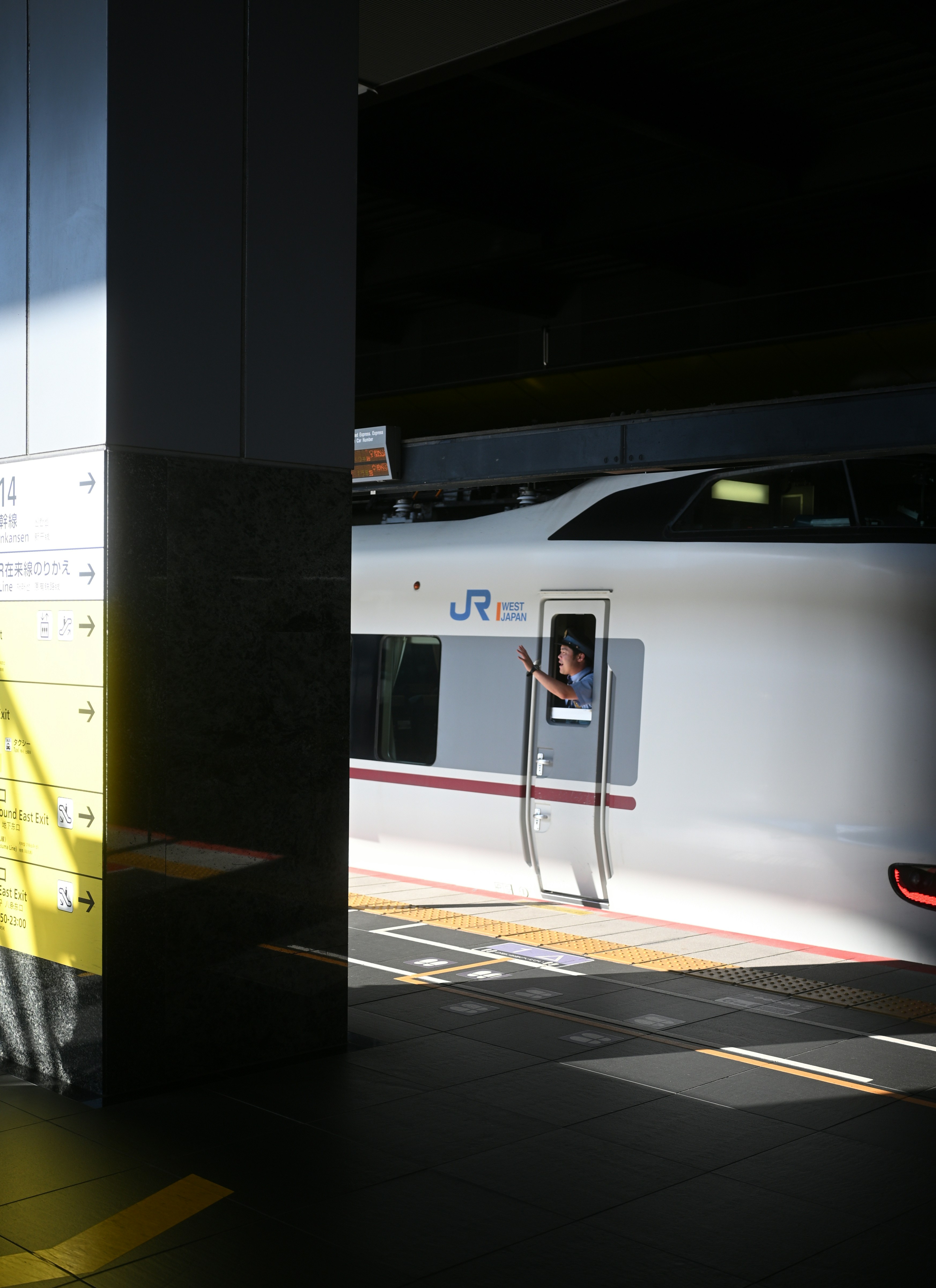 Ein weißer Zug, der neben einer Ladeplattform über die Gleise fährt