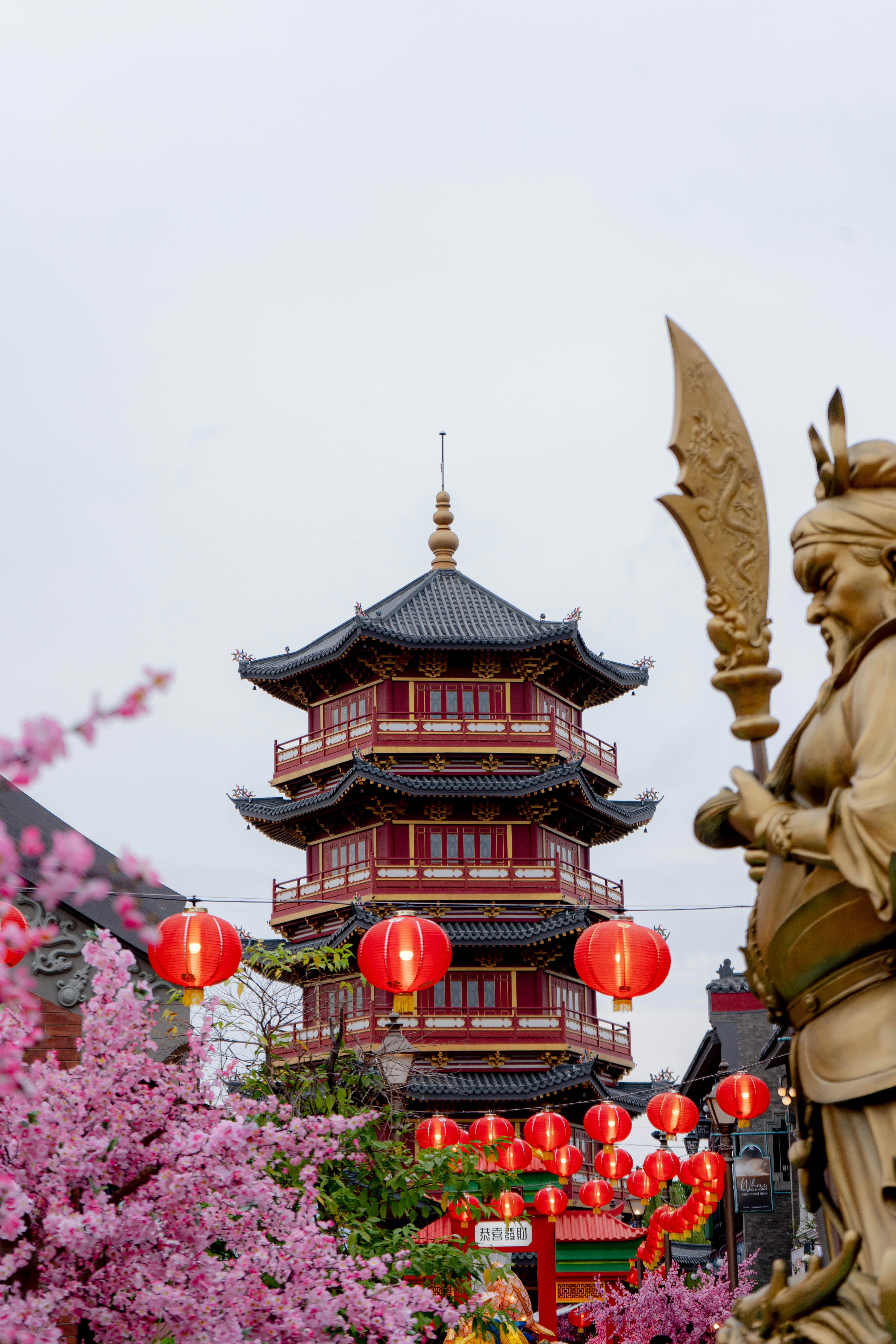 A statue of a woman holding a sword in front of a pagoda