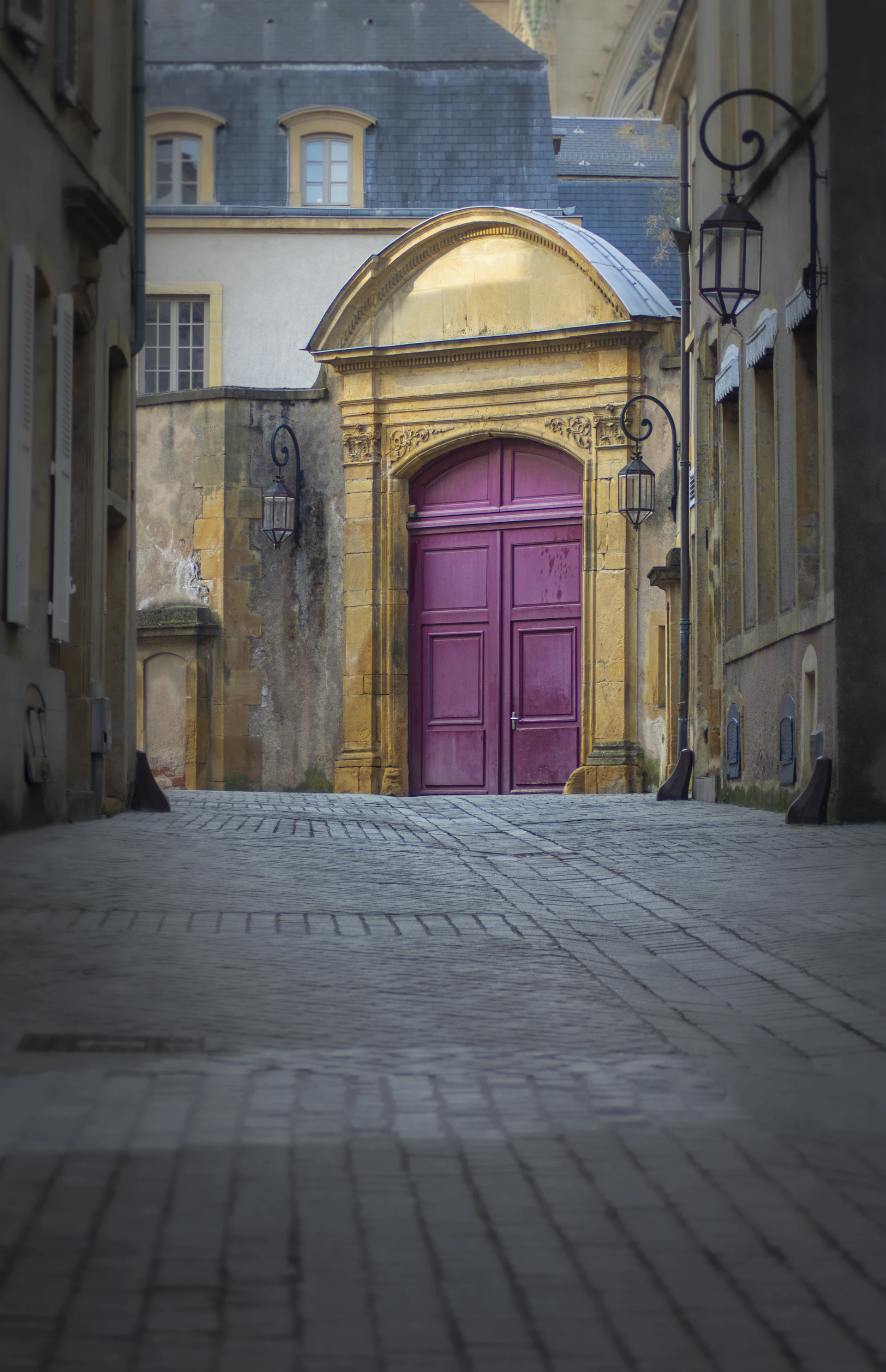 A purple door is in the middle of a cobblestone street