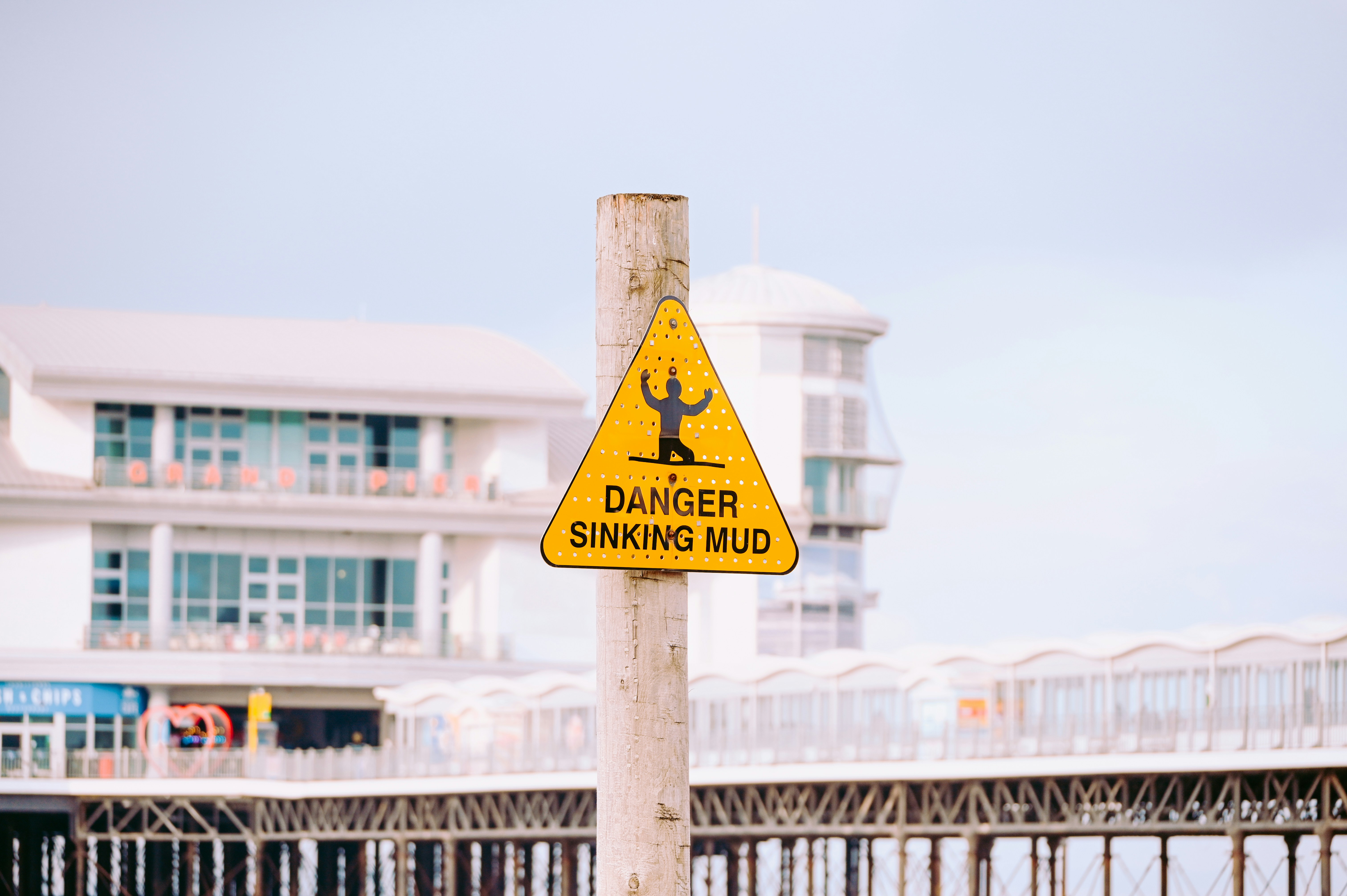A yellow sign on a pole in front of a pier