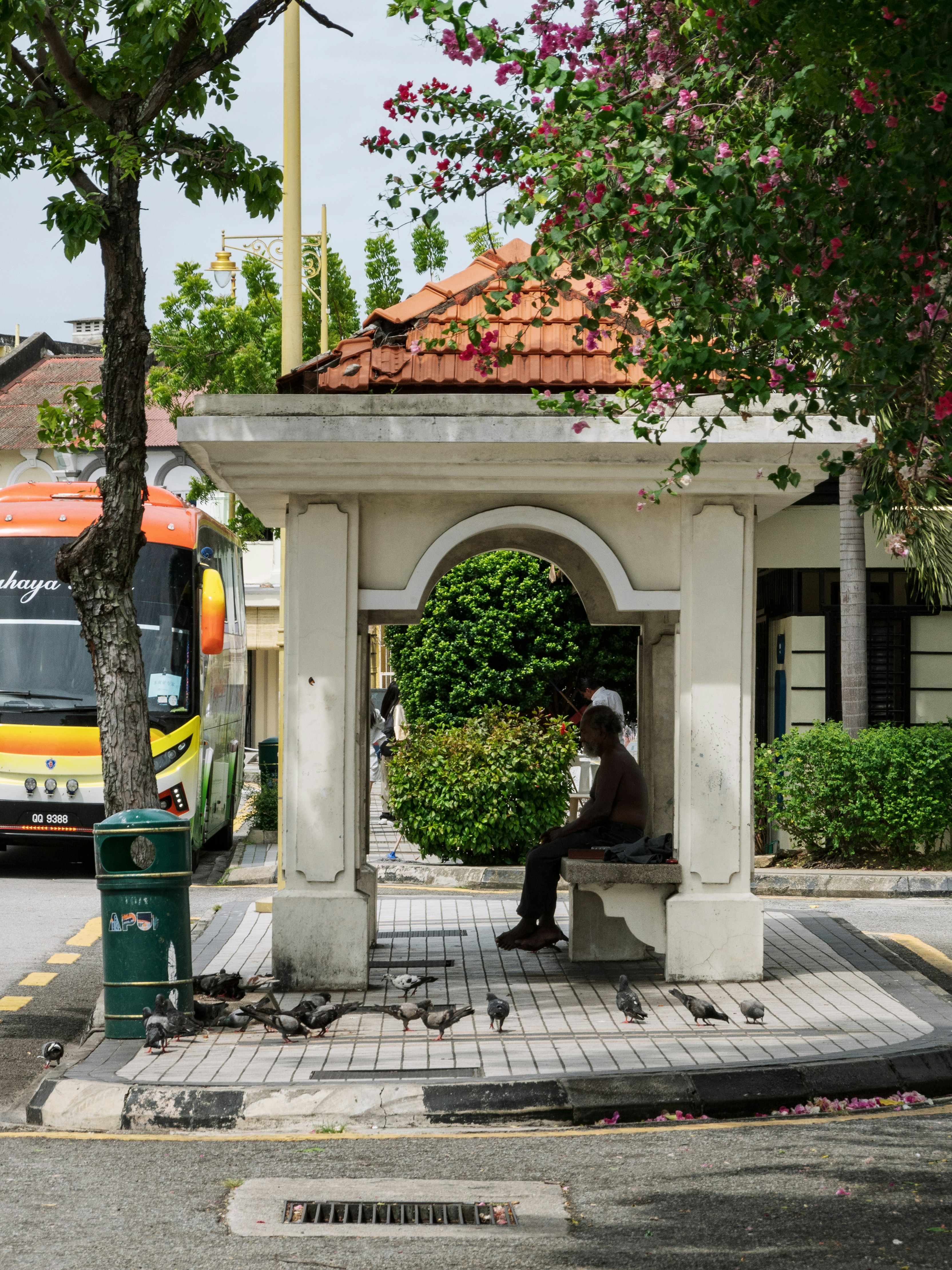 A man sitting on a bench in front of a bus