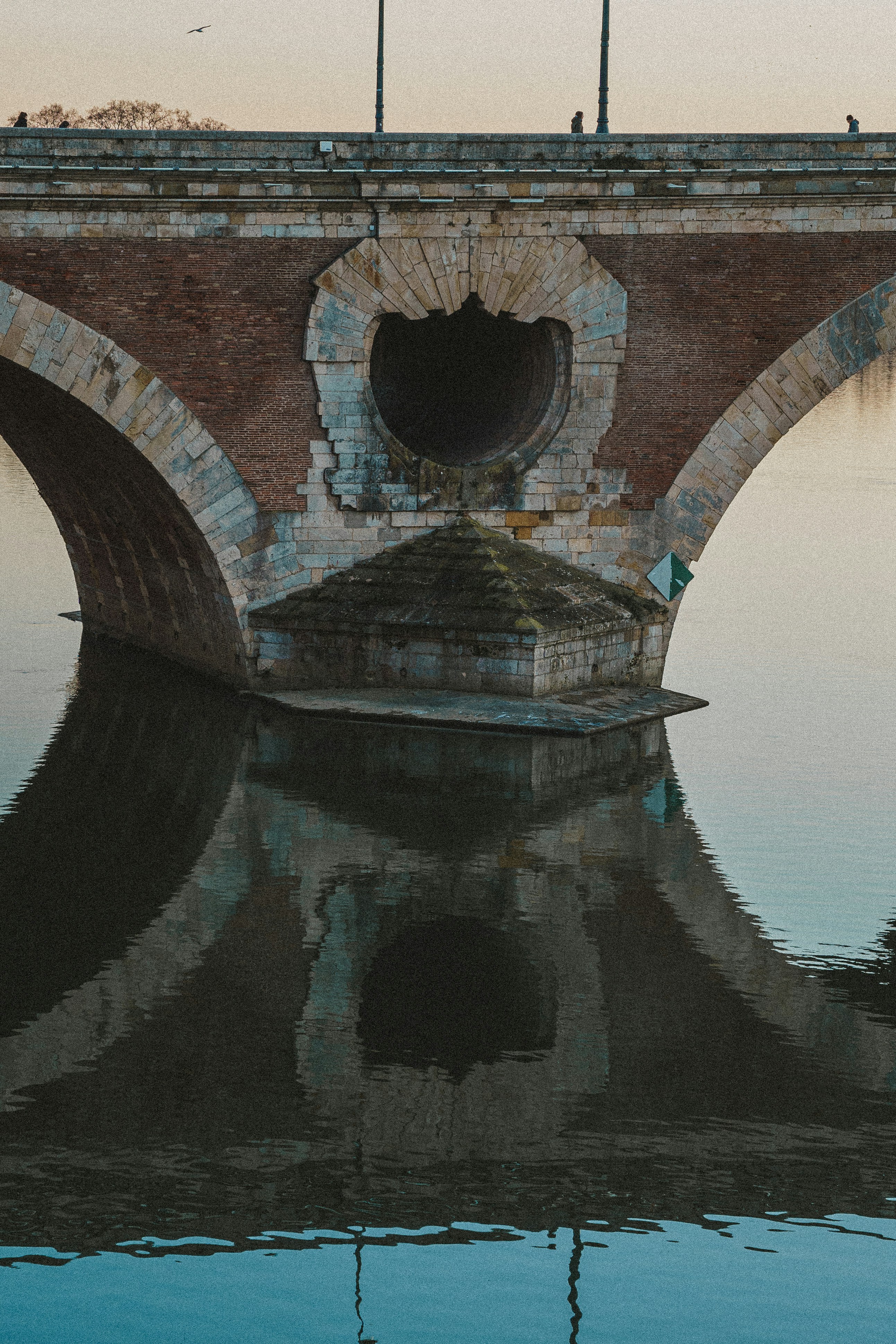 Un pont au-dessus d’un plan d’eau avec un oiseau perché dessus