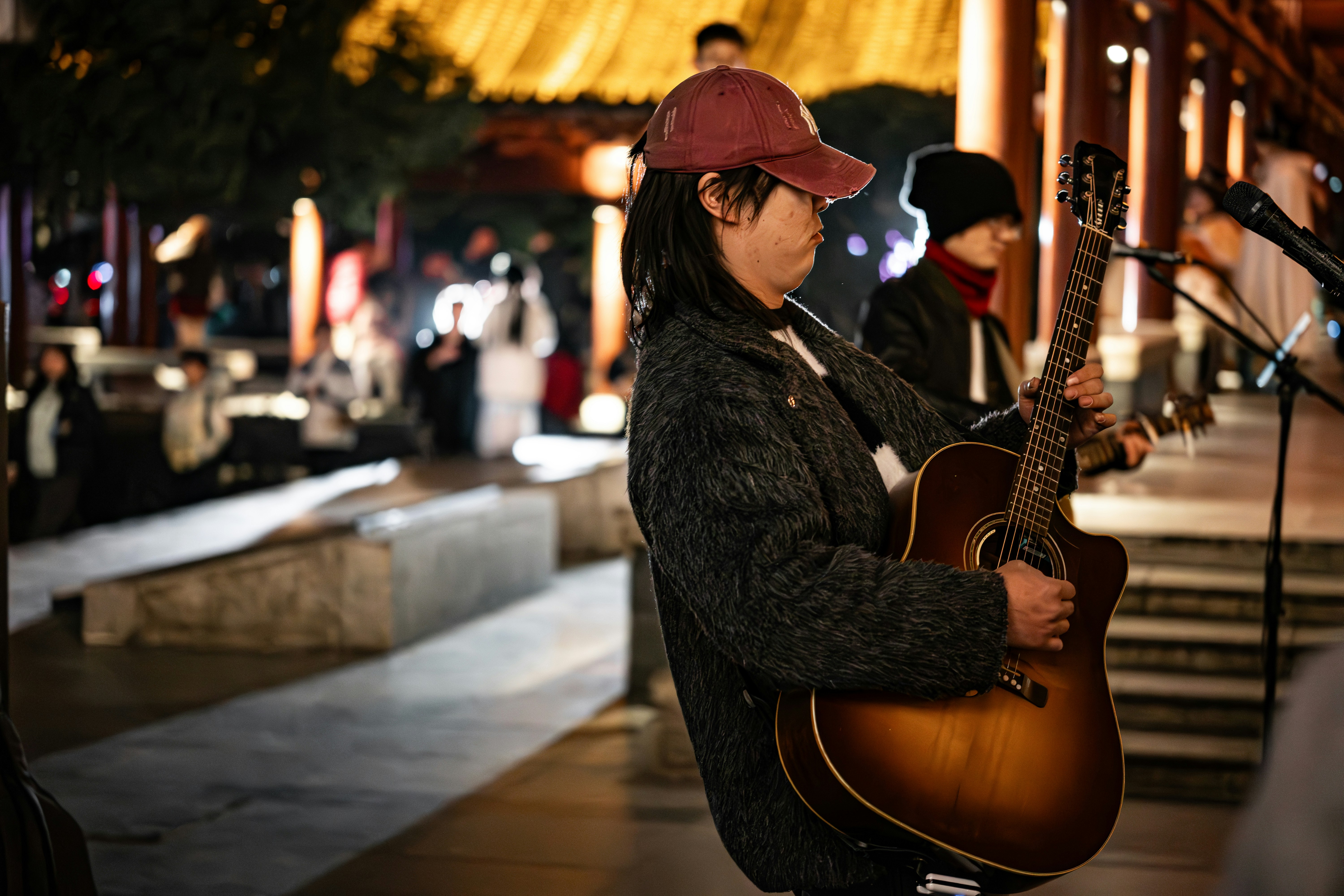 A man holding a guitar while standing on a sidewalk