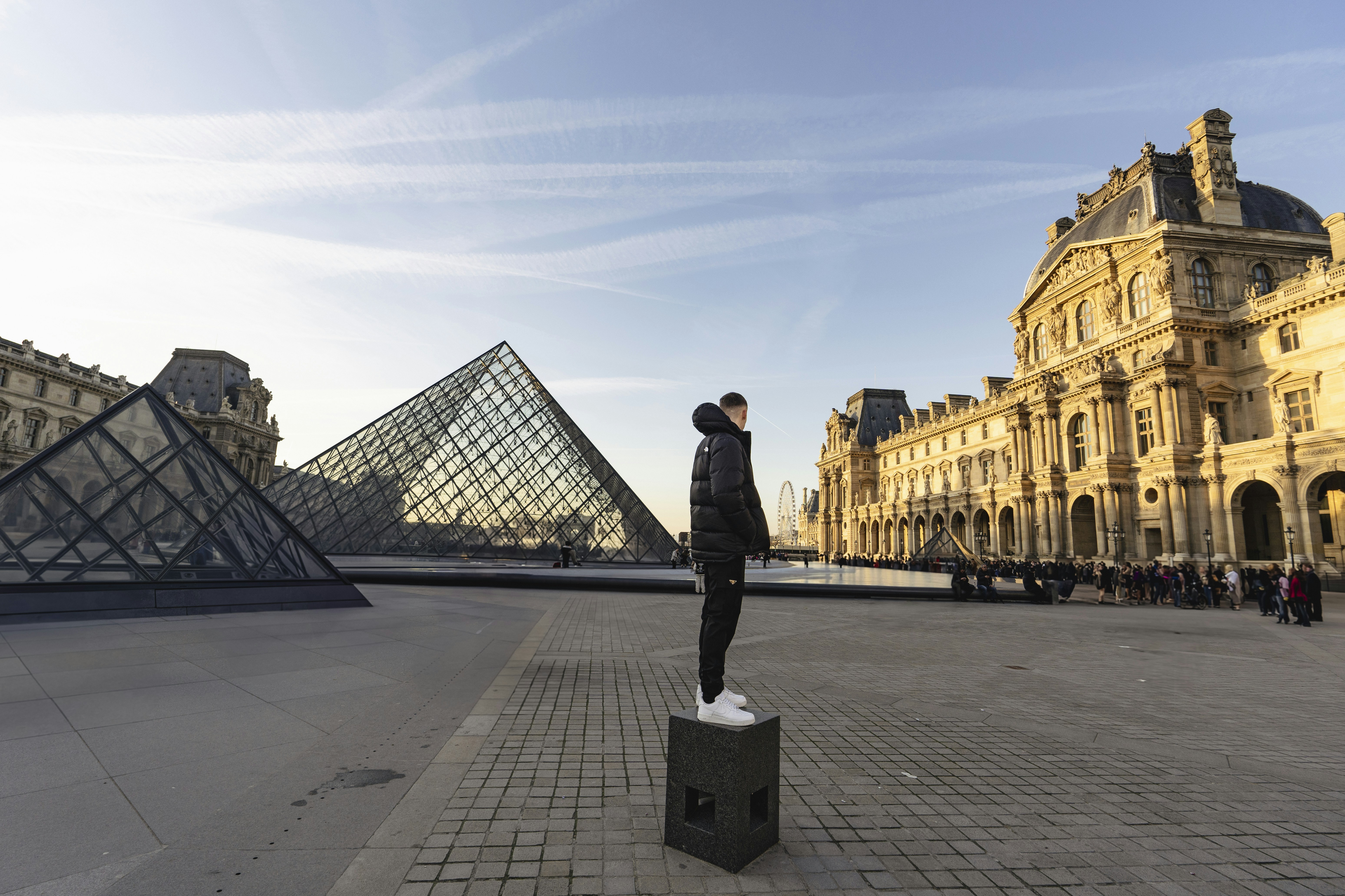 A man standing on top of a box in front of a pyramid
