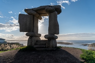 A stone sculpture sitting on top of a dirt field