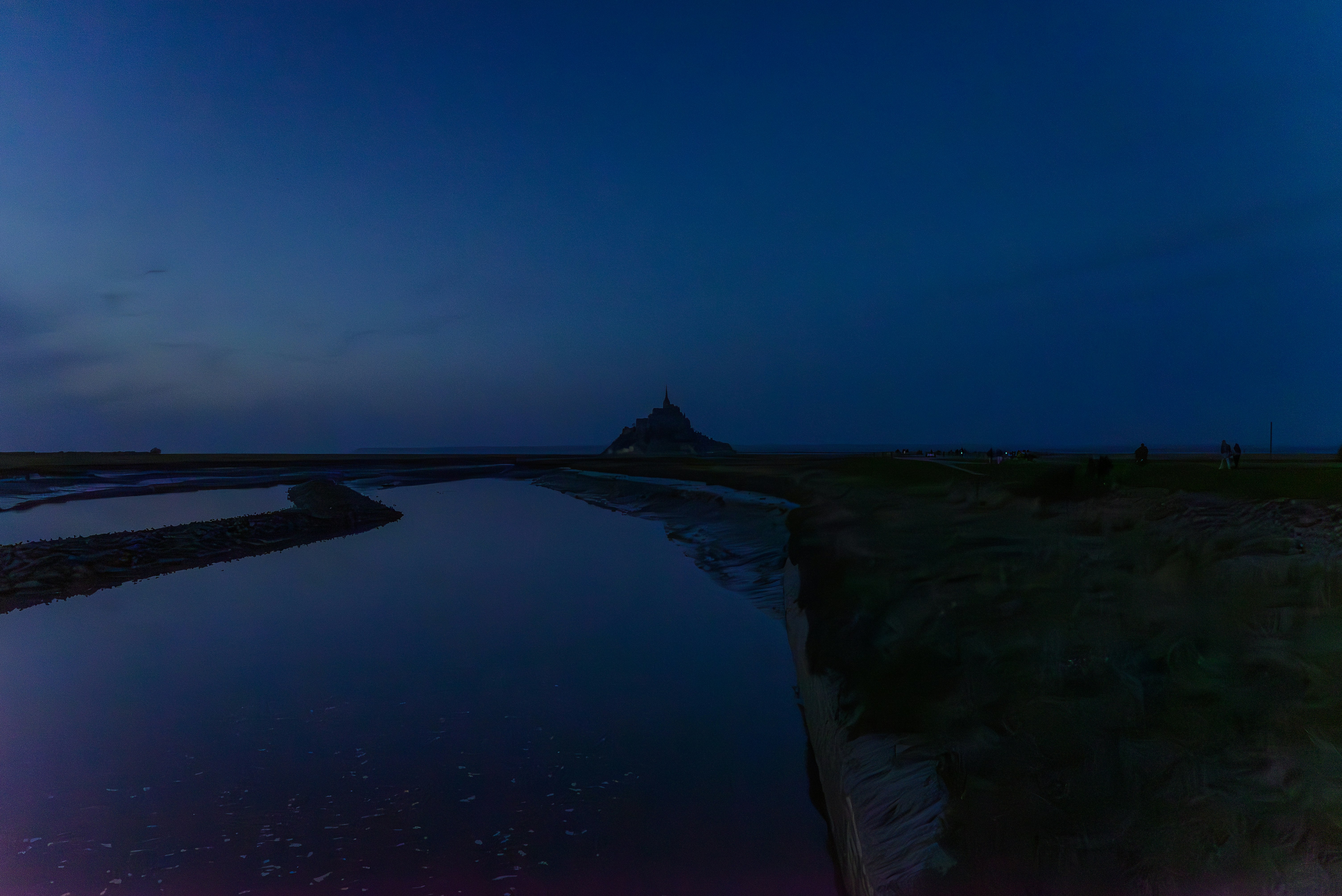 A night scene of a body of water with a hill in the background