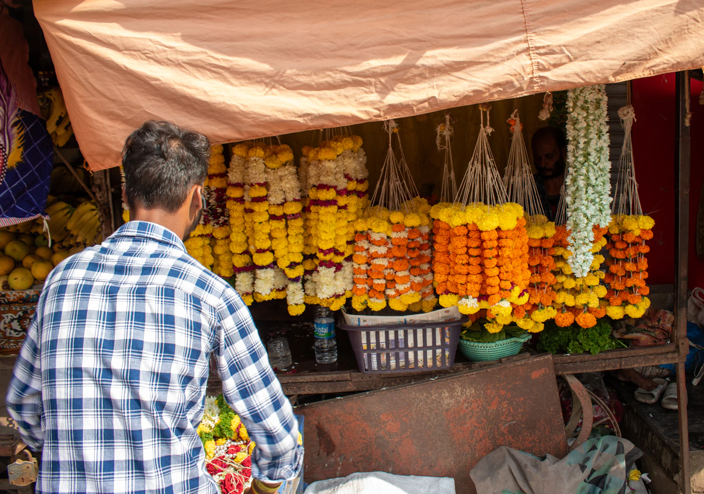 Vendor standing in front of his fruit stand at a busy Indian street market