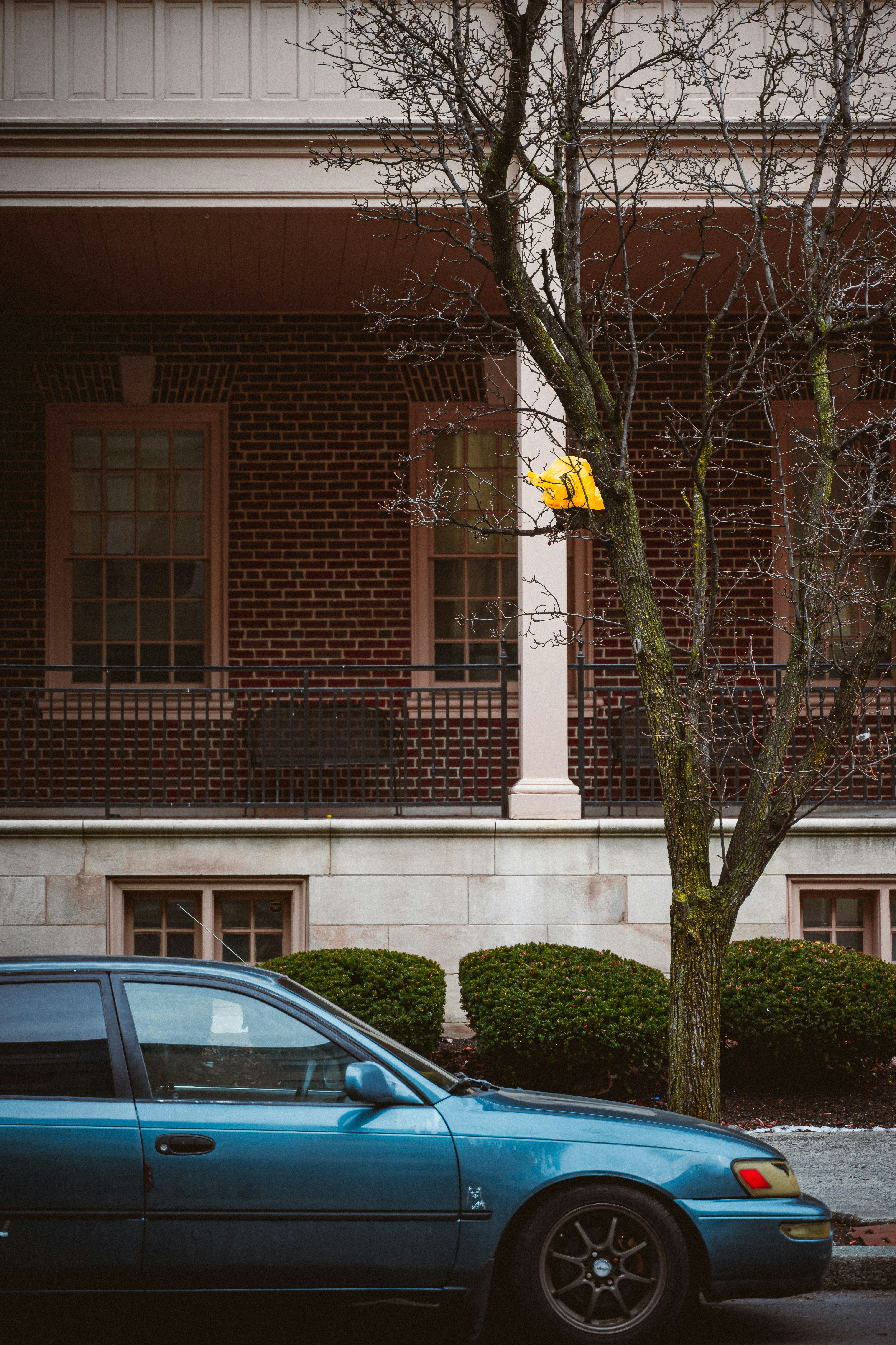A blue car parked in front of a tall brick building