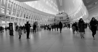 A black and white photo of people walking through a building