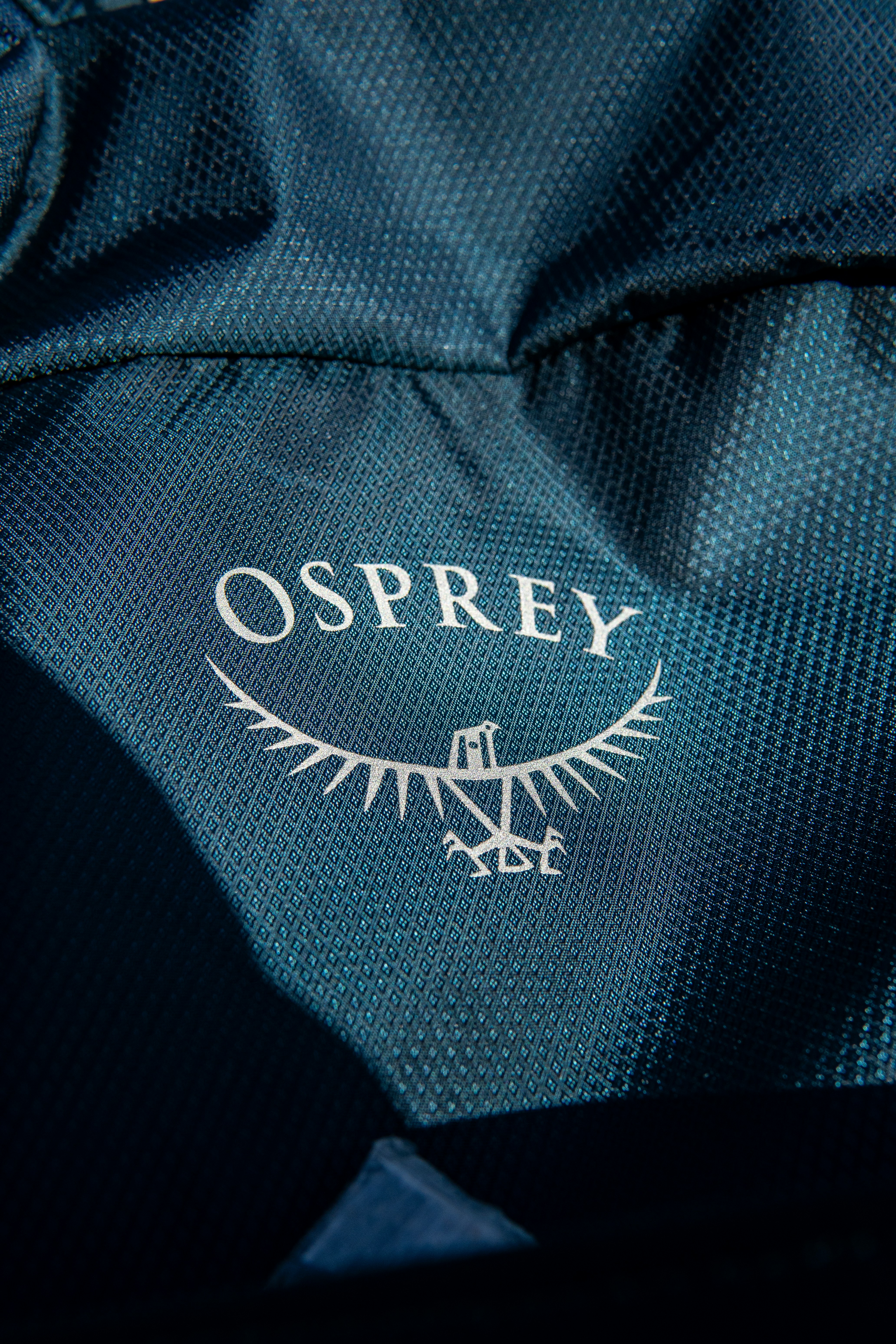 A close up of a blue jacket with an osprey logo on it