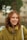 A woman with red hair is smiling and holding a white bag