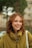 A woman with red hair is smiling and holding a white bag