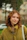 A woman with red hair is standing in the grass