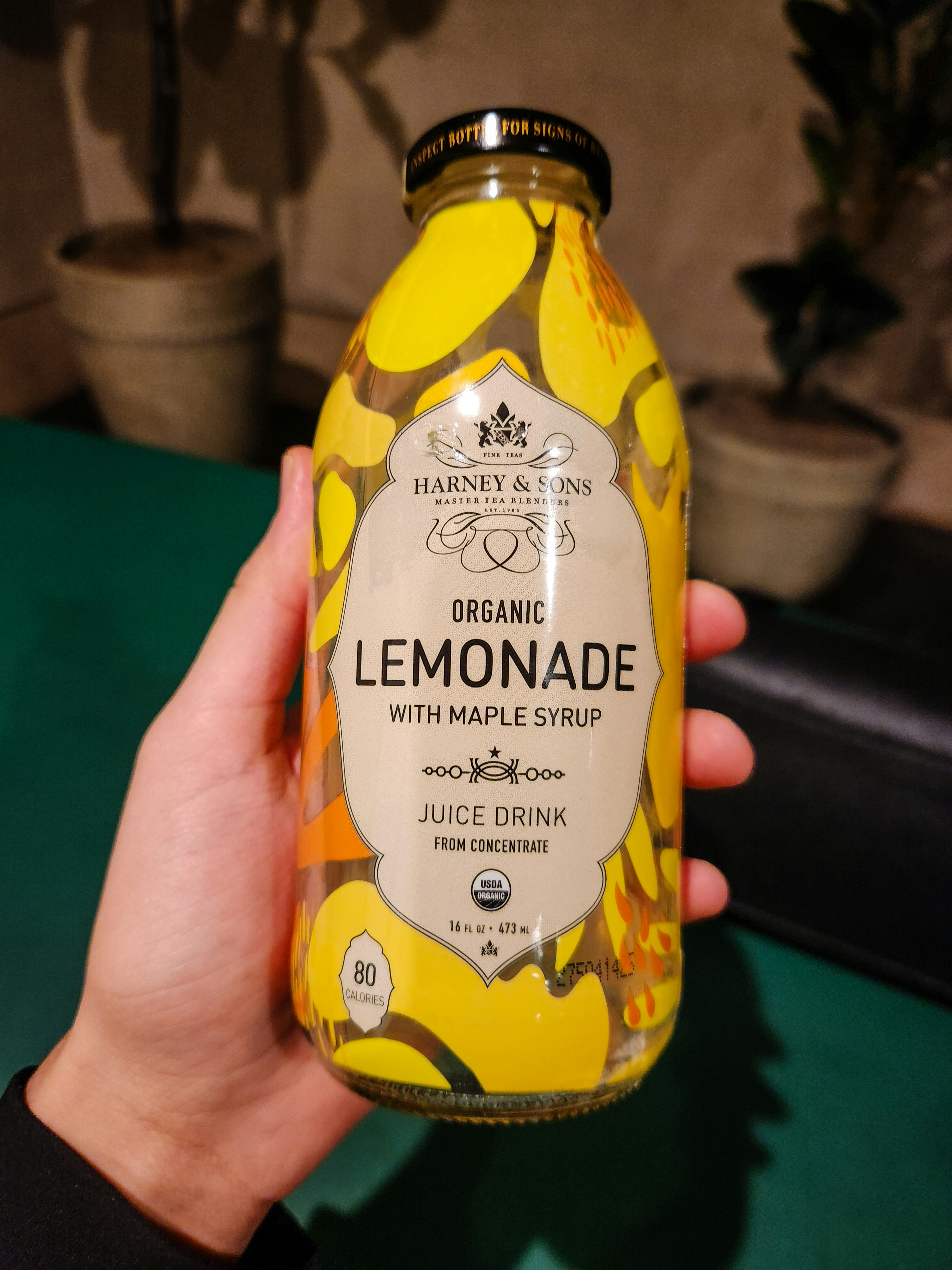 A person holding a bottle of lemonade in their hand