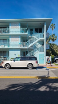 A white car parked in front of a blue building