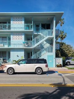 A white car parked in front of a blue building